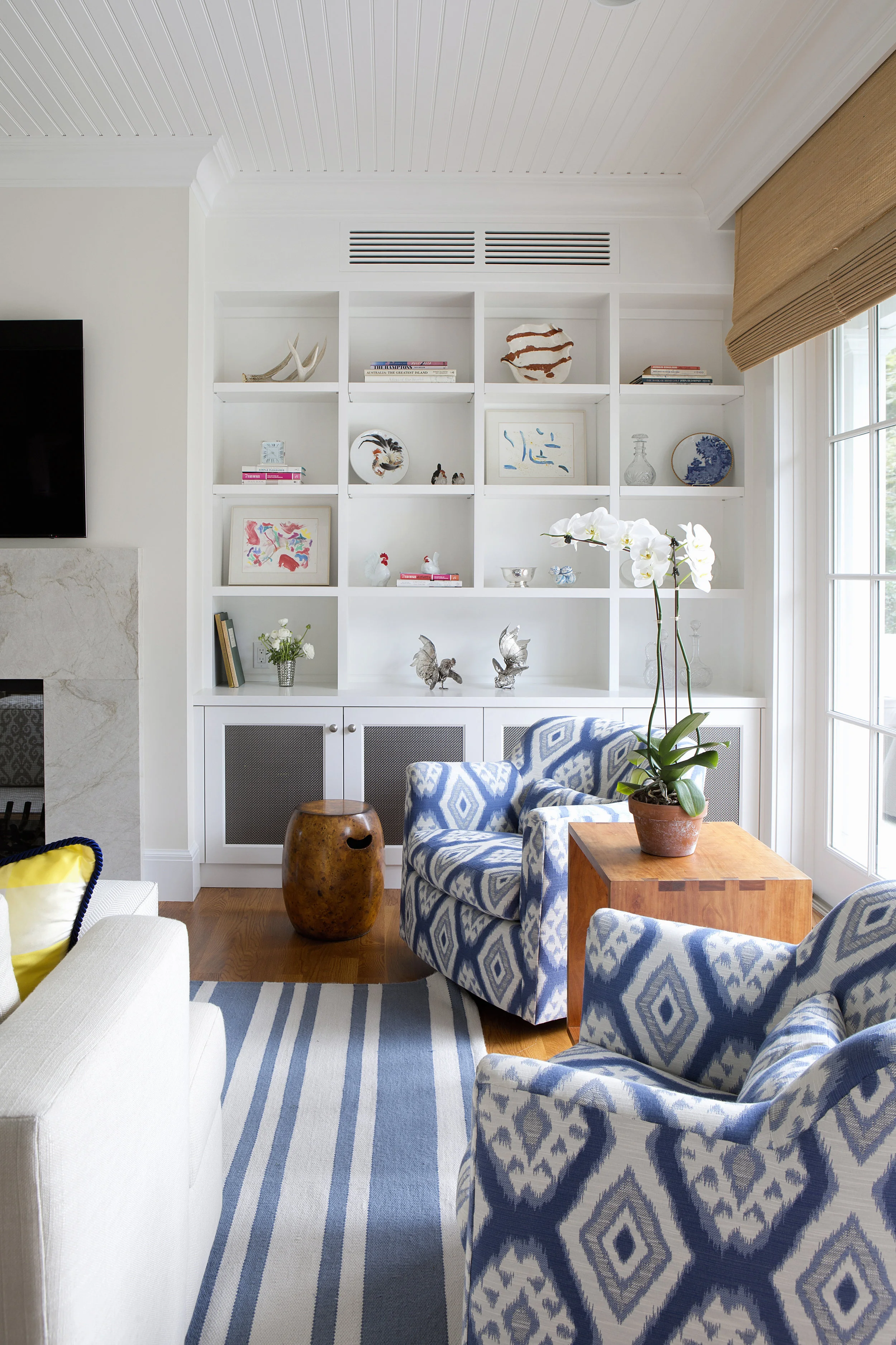 In the family room custom built-ins for the clients electronics include black interiors to camouflage them and wire mesh panels of stainless steel for ventilation 