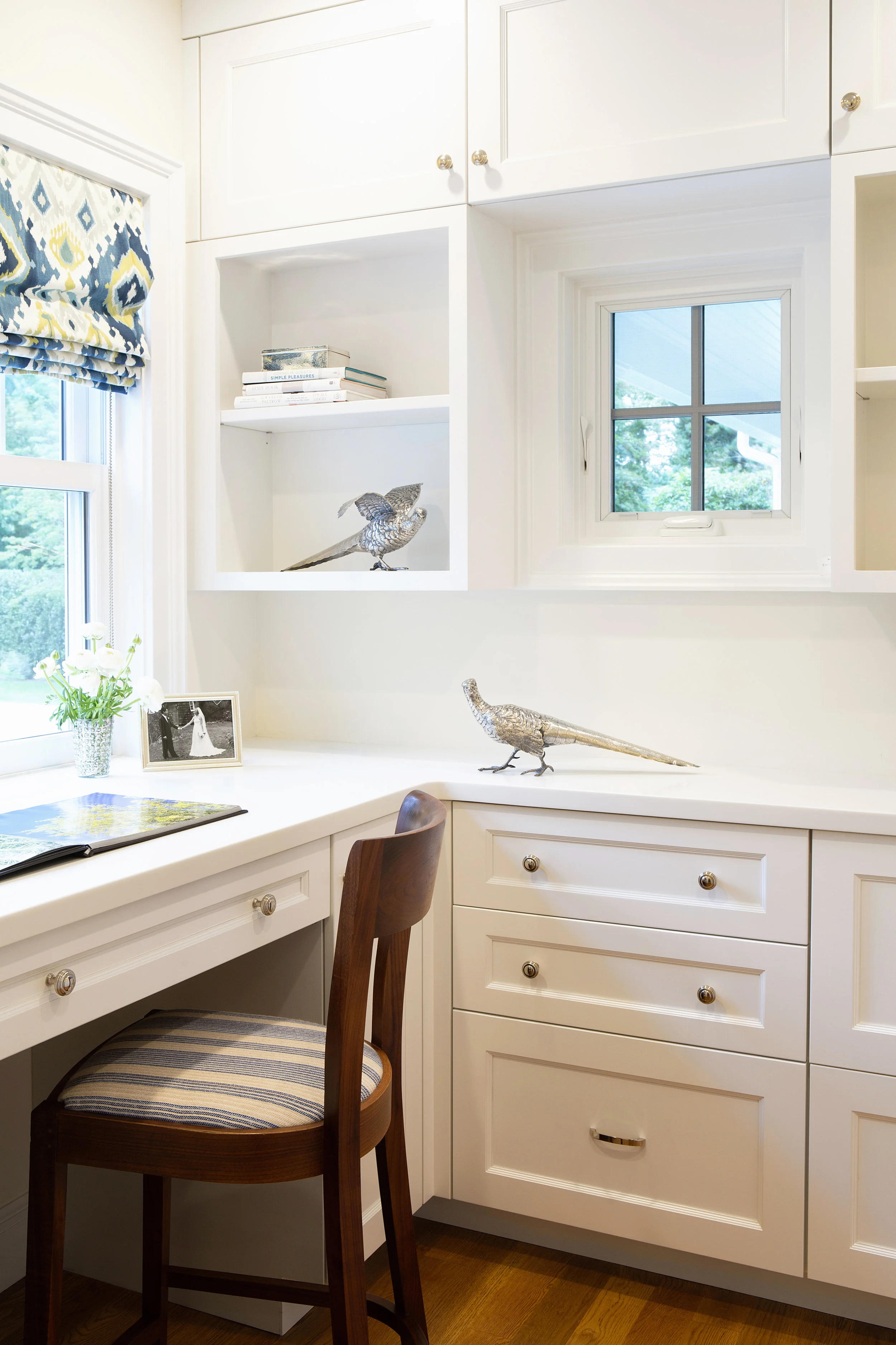A cozy room off the side entrance to the house serves as a compact home office, with built-in cabinets and Corian surfaces. The space lets the client keep all her projects and paperwork behind closed doors, in the same fresh, streamlined style as the rest of the house.
