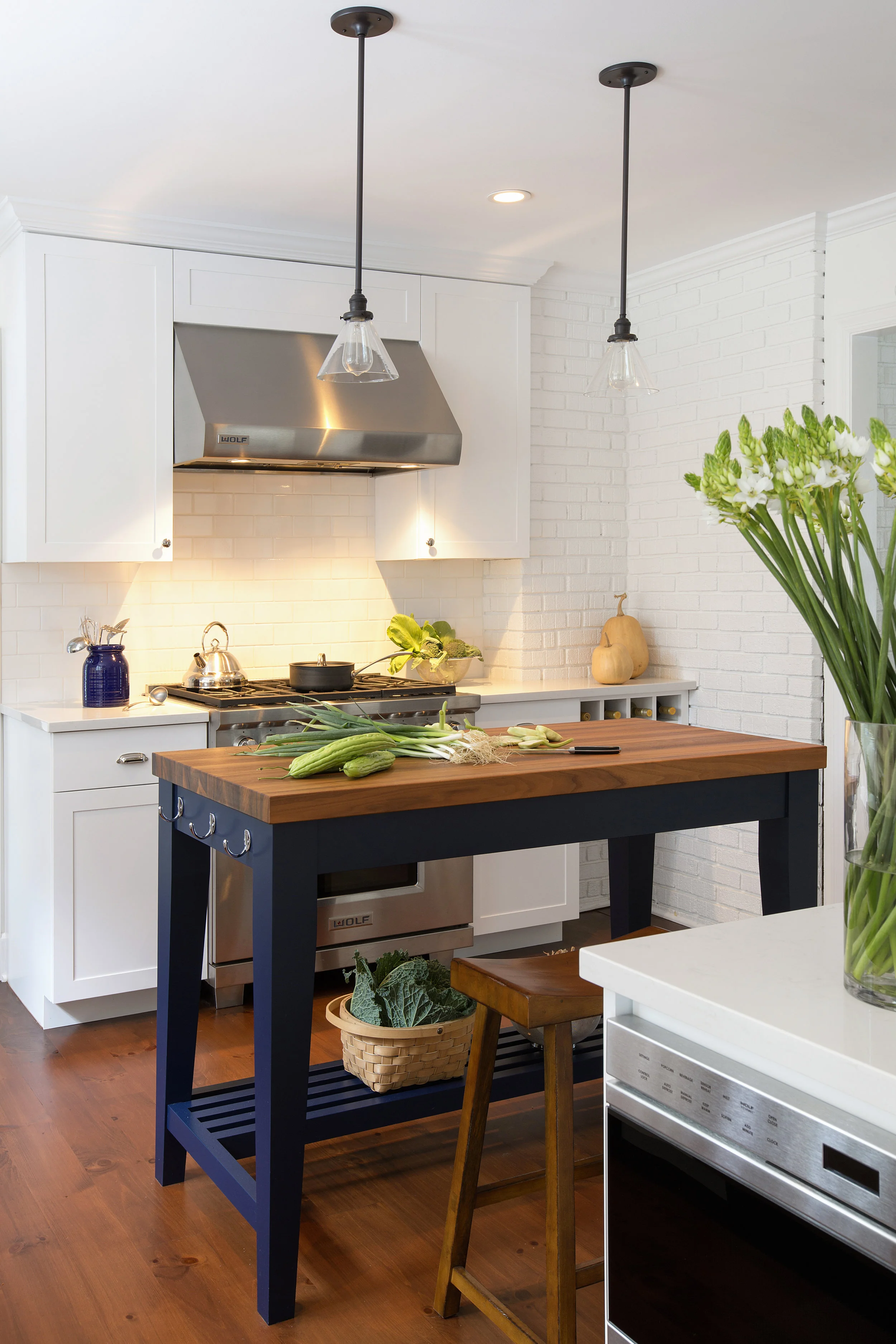 The base of the island is painted a rich navy blue, a beautiful complement to the warm walnut tones of the island countertop and the walnut-stained pine flooring. 