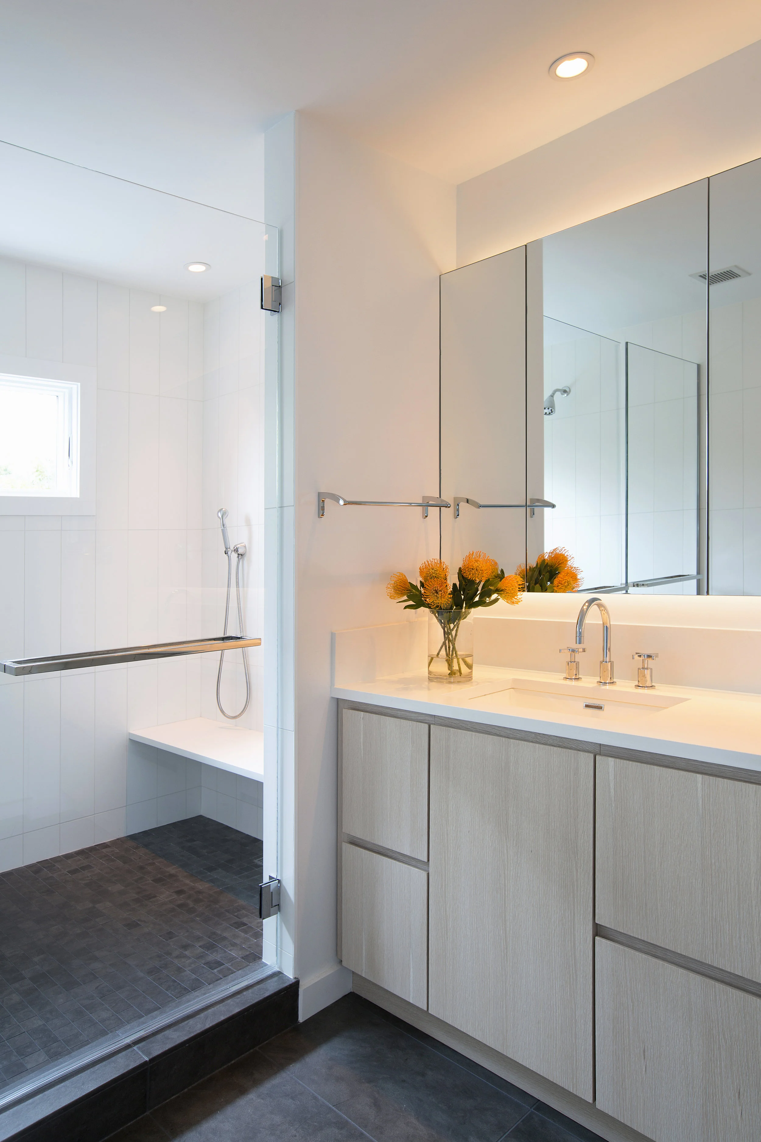 In the master bath LED lighting from both above and below the medicine cabinet offers bright, flattering light. All the bathrooms utilize the same large format white matte ceramic tile. 
