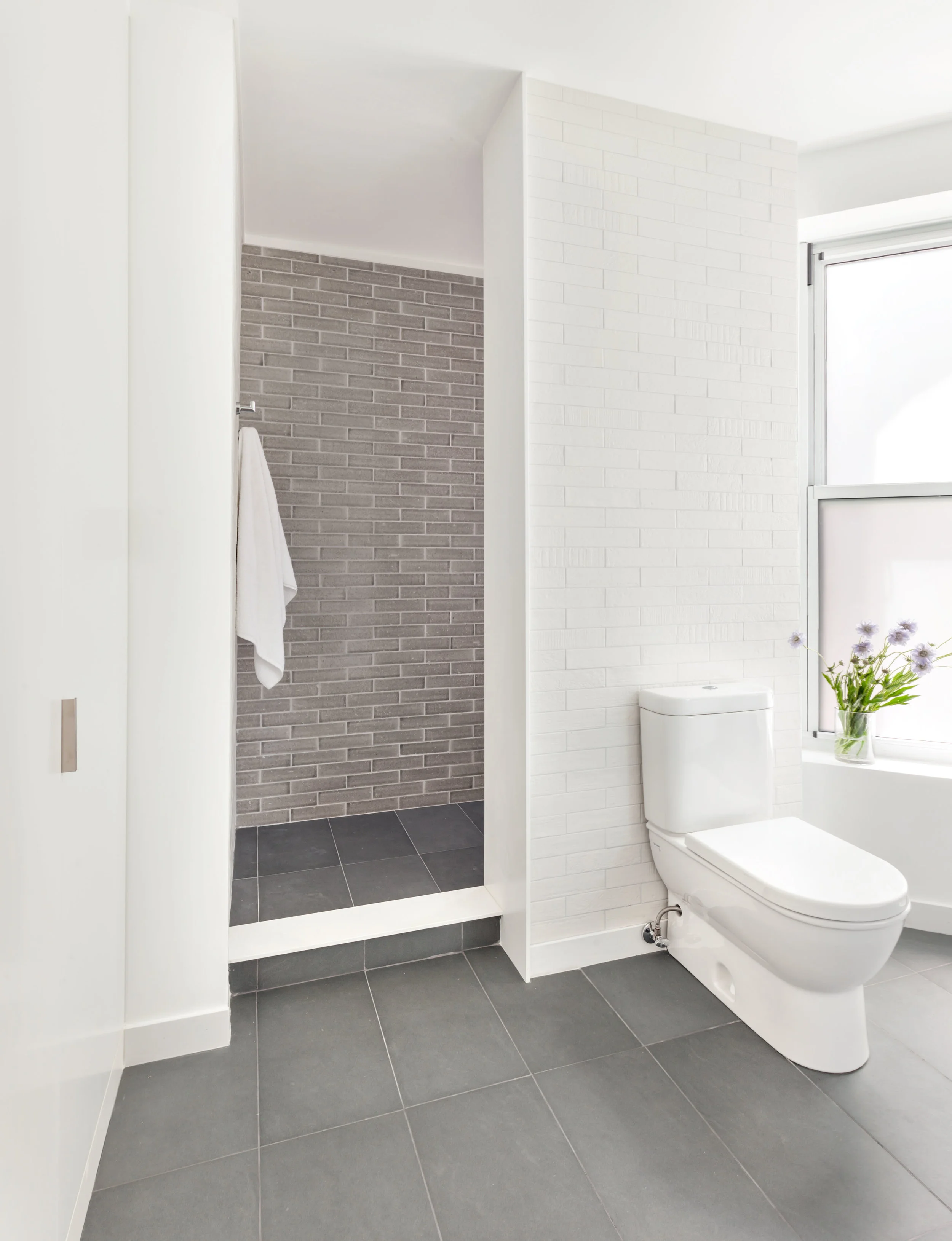 Ensuite master bathroom with white, brick textured tile and gray accent tile in the shower.