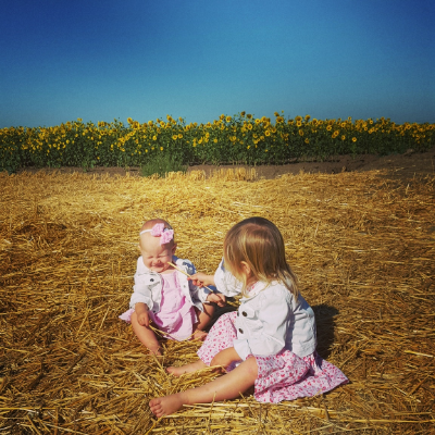 When you dress your kids in darling matching outfits and put them in a sunflower field to capture a magical moment and your toddler uses this opportunity to poke her sister in the eye with hay.