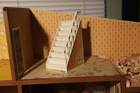 I decided to remove the stairwell for easier access to the floor and because I plan to remove the railing to update the look of it. I want to keep the stairwell in the house because it makes a nice cubby space from the backside, and I plan to make that a wooded wonderland. Right now, I am wondering what to do with all this exposed wood...errr masonite. Perhaps some interesting floor tile possibilities....