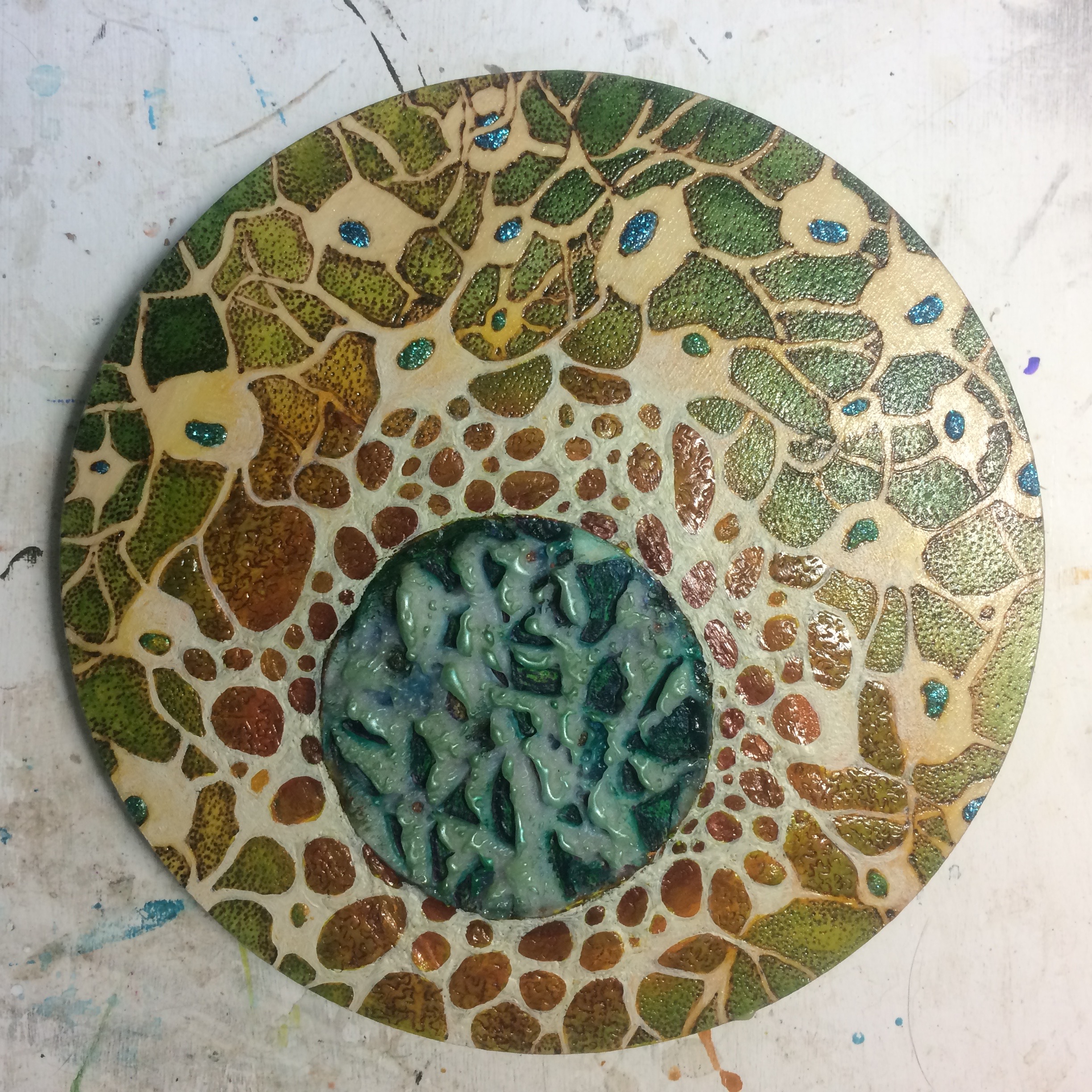 (A) Cut square into circle, reverse painted pebbles. (K) Added jute around edge, green pastel. (A) Tied knot. 