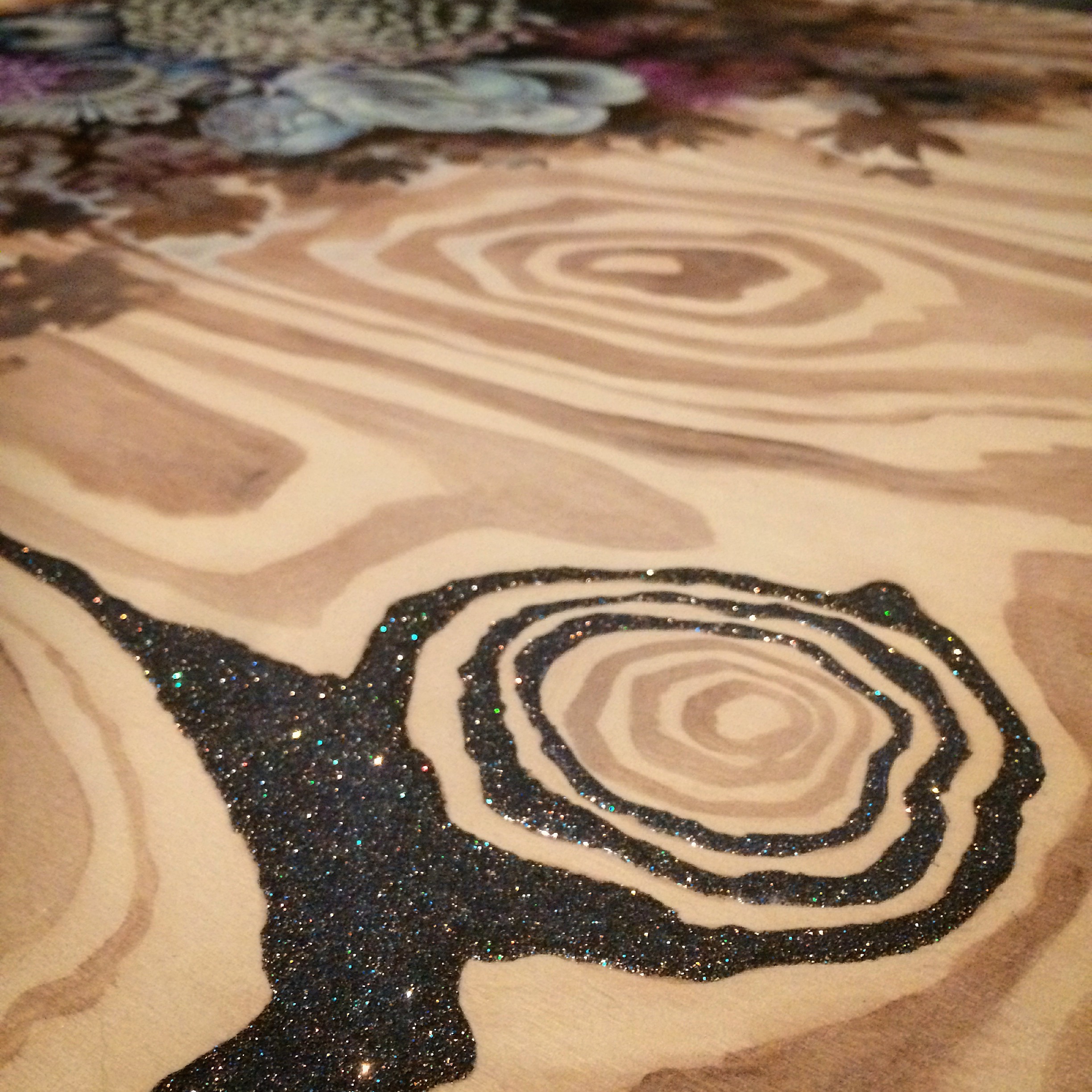 Adding glitter mixed with pouring medium to wood grain. 