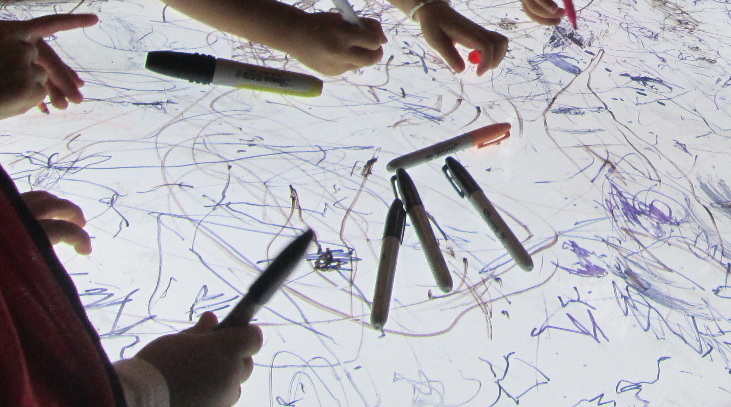3s + 4s draw on plexiglass atop a light box, while watching a video of Jackson Pollock toss paint onto a translucent surface.