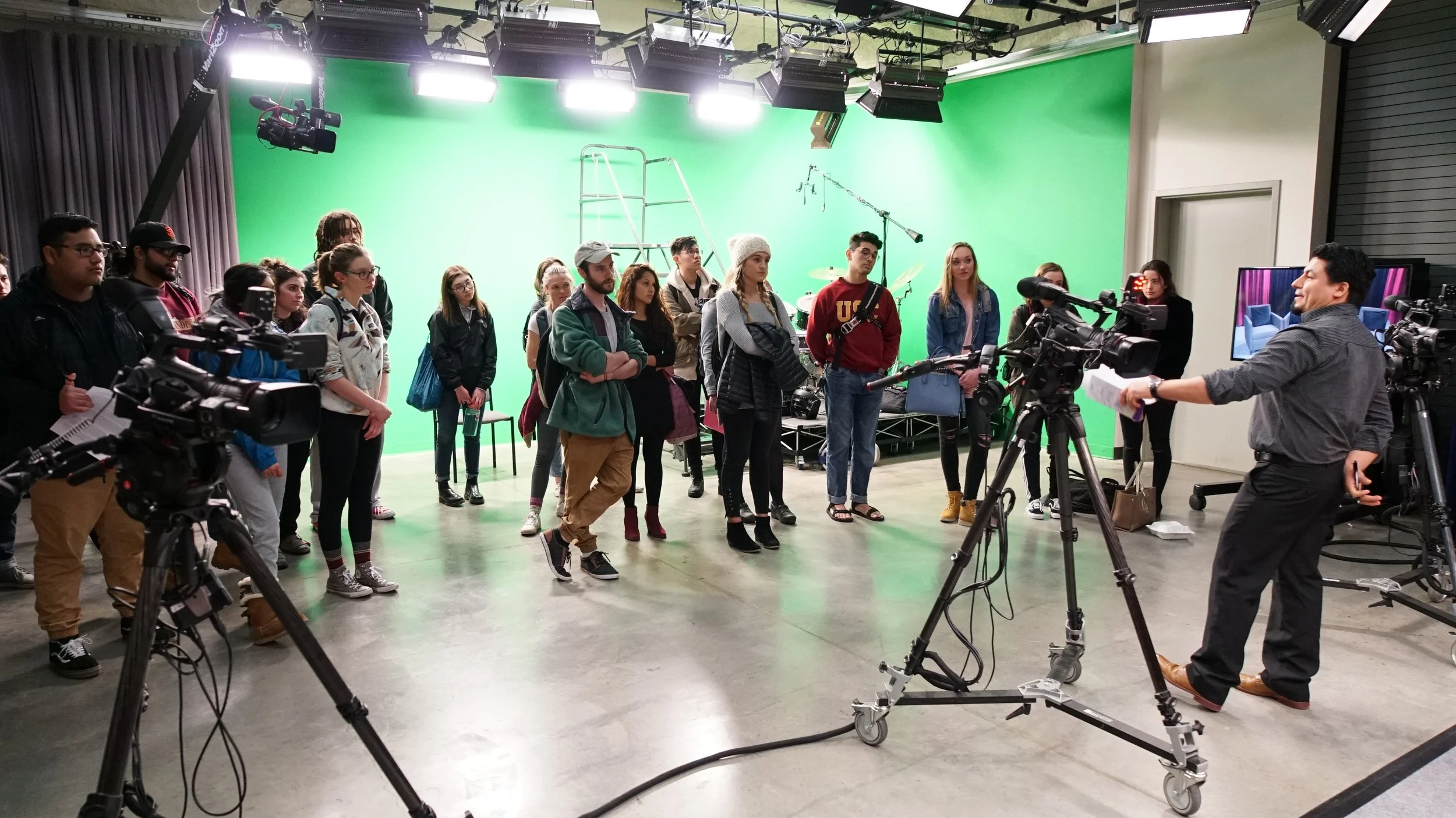 Group of people standing in a studio with a green screen behind them