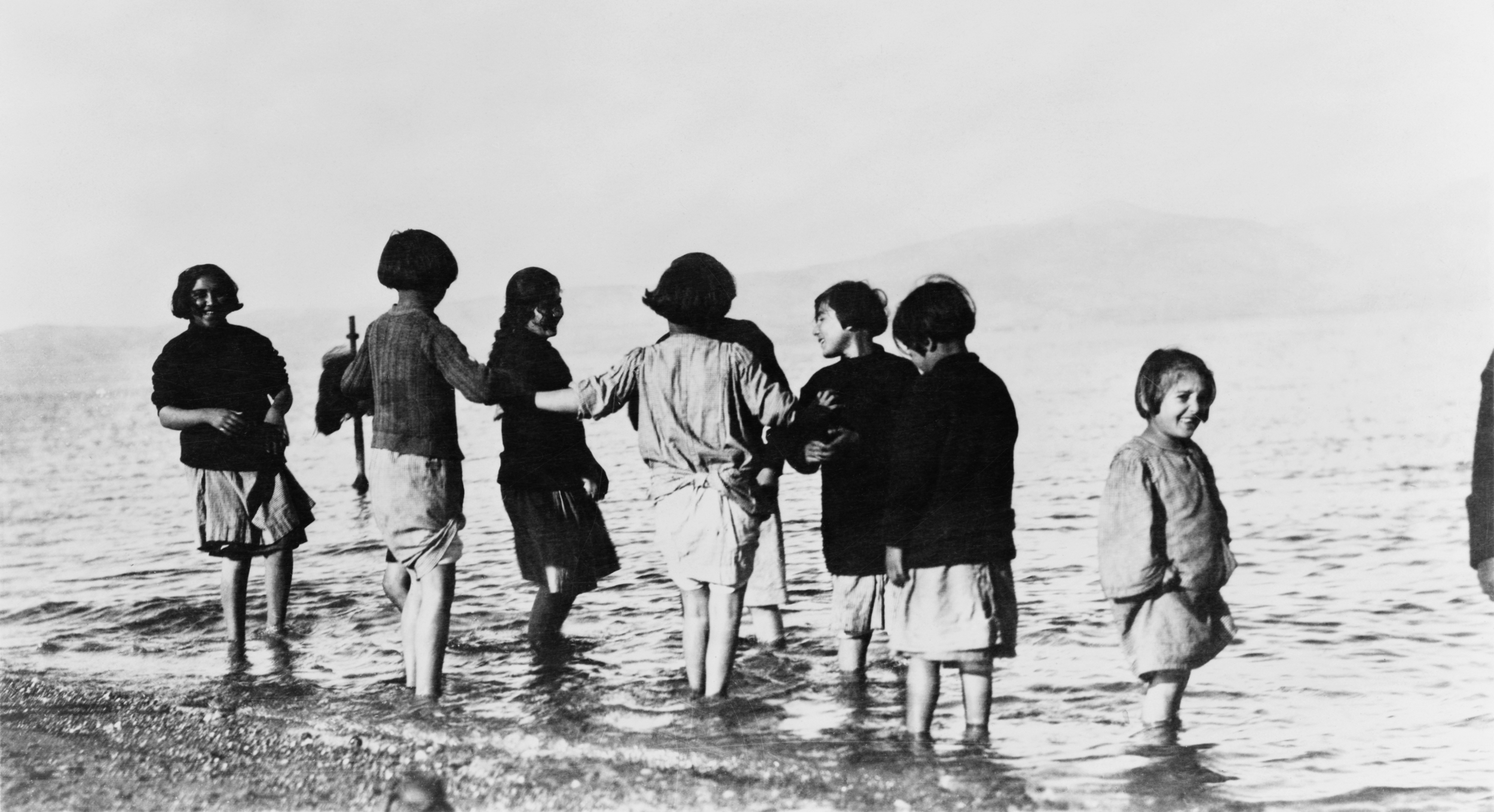 Greek and Armenian refugee children in the sea near Marathon, Greece after their departure from Turkey. The children -- all orphans -- had never seen the sea before. Photo licensed through Wikimedia Commons. 