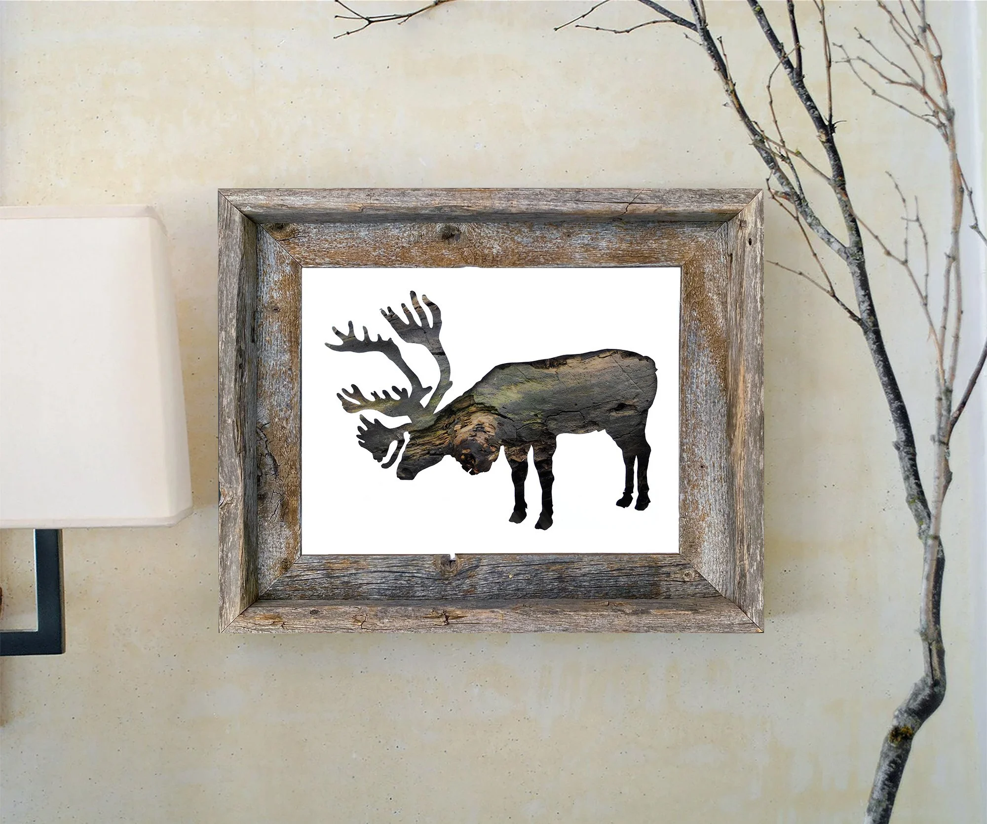 Framed caribou bark art print displayed in a rustic wood frame against a light wall with natural branches.