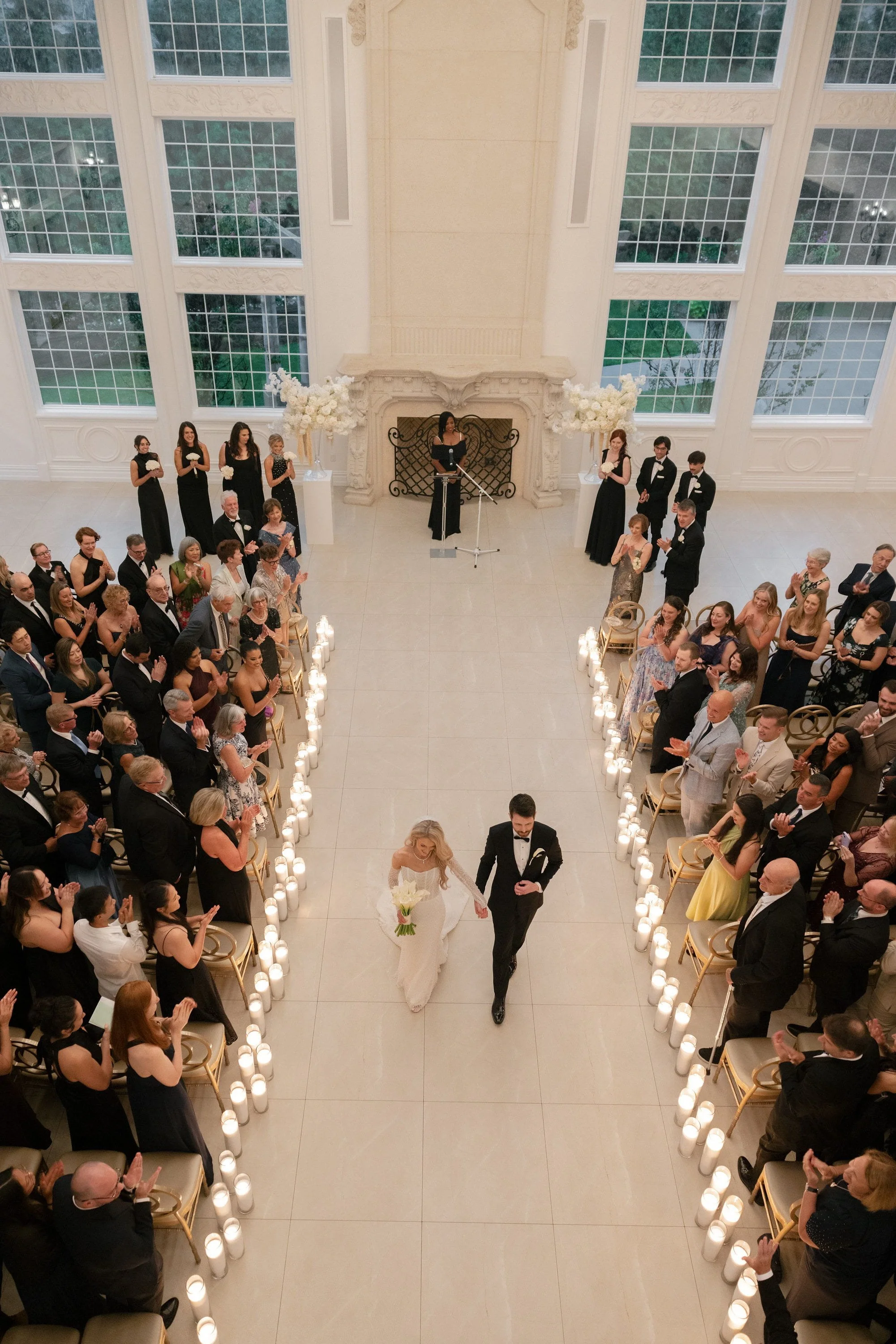 Aerial view of Caroline and Brett walking back down the aisle as their guests look on after the wedding ceremony