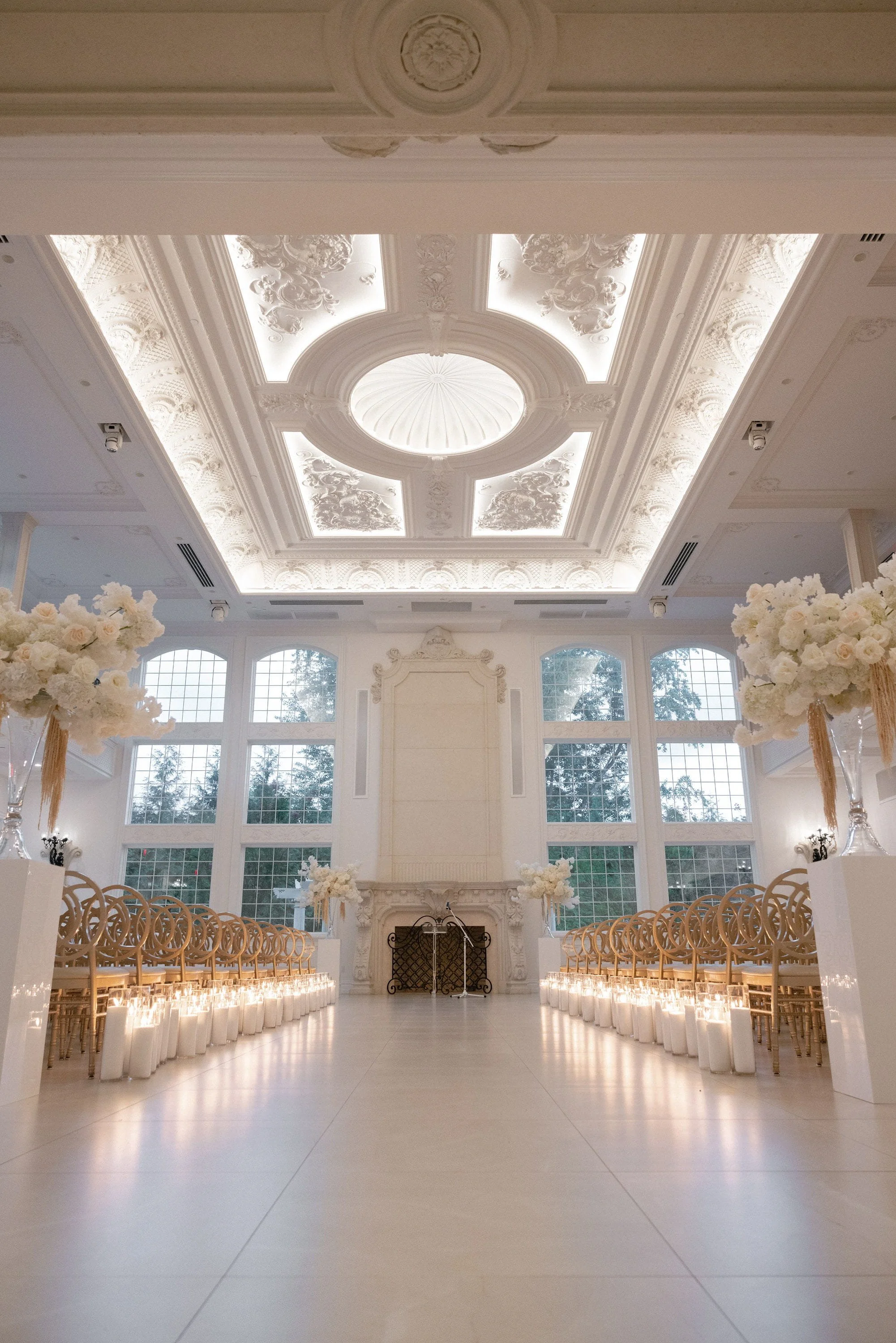 Indoor wedding ceremony space at Florentine Gardens in River Vale, NJ with candlelit aisle, gold chairs and white florals