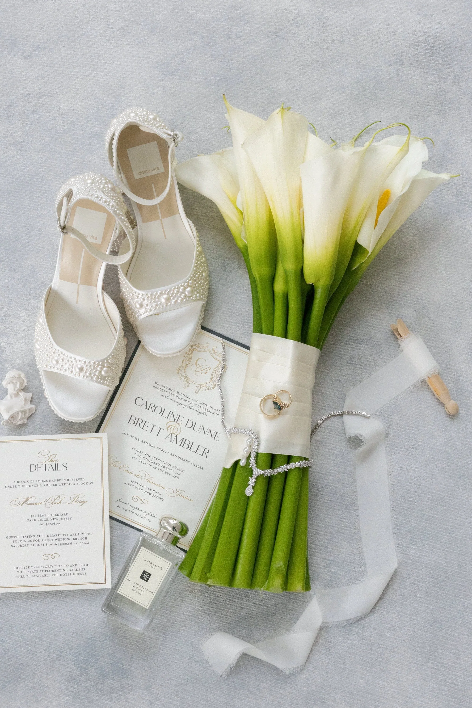 Caroline’s bridal shoes, calla lily bouquet, wedding stationery and perfume arranged before the ceremony