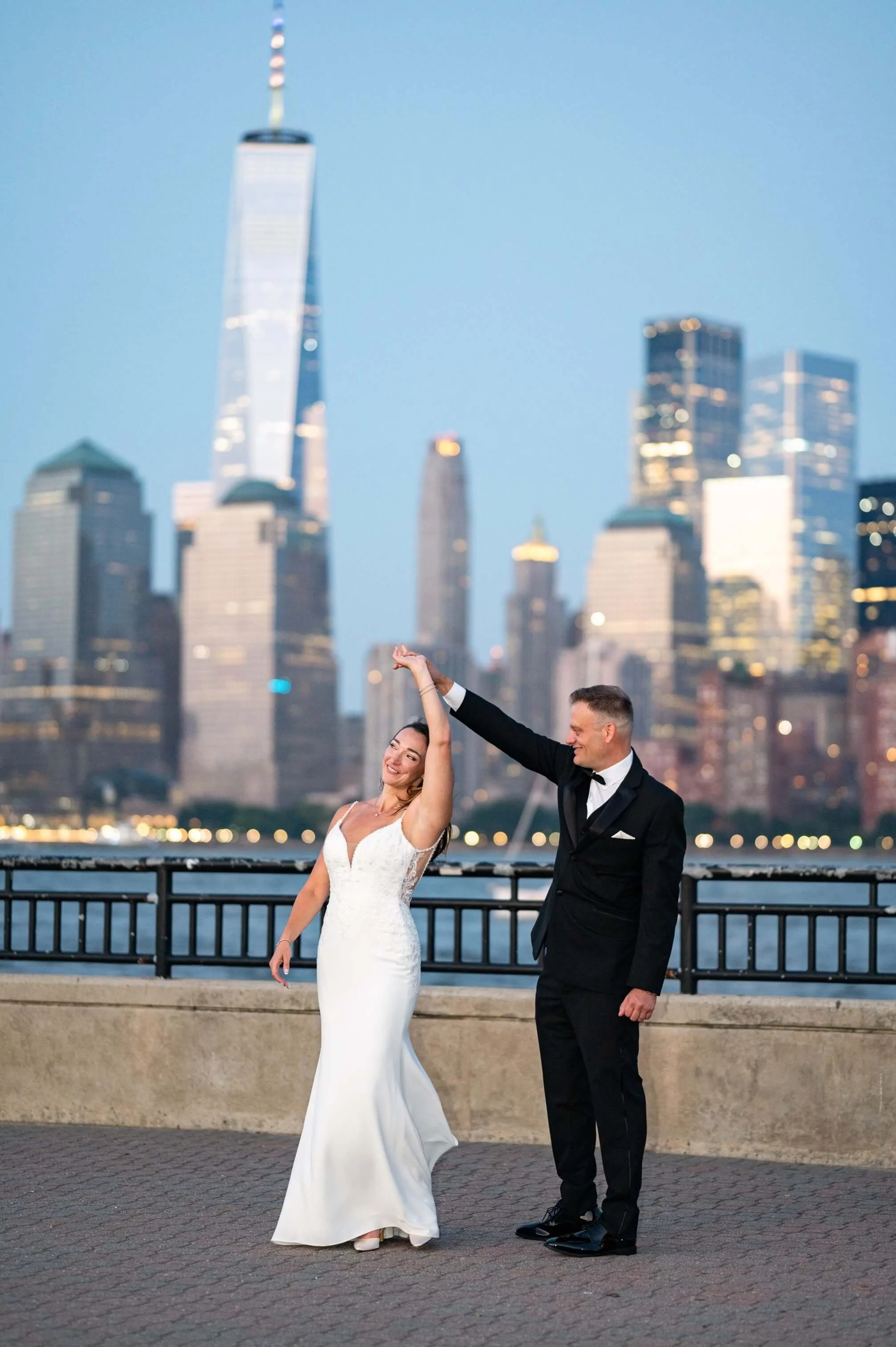 Bride being twirled by groom during an intimate elopement at Liberty State Park in Hudson County, New Jersey, with the New York City skyline in the background