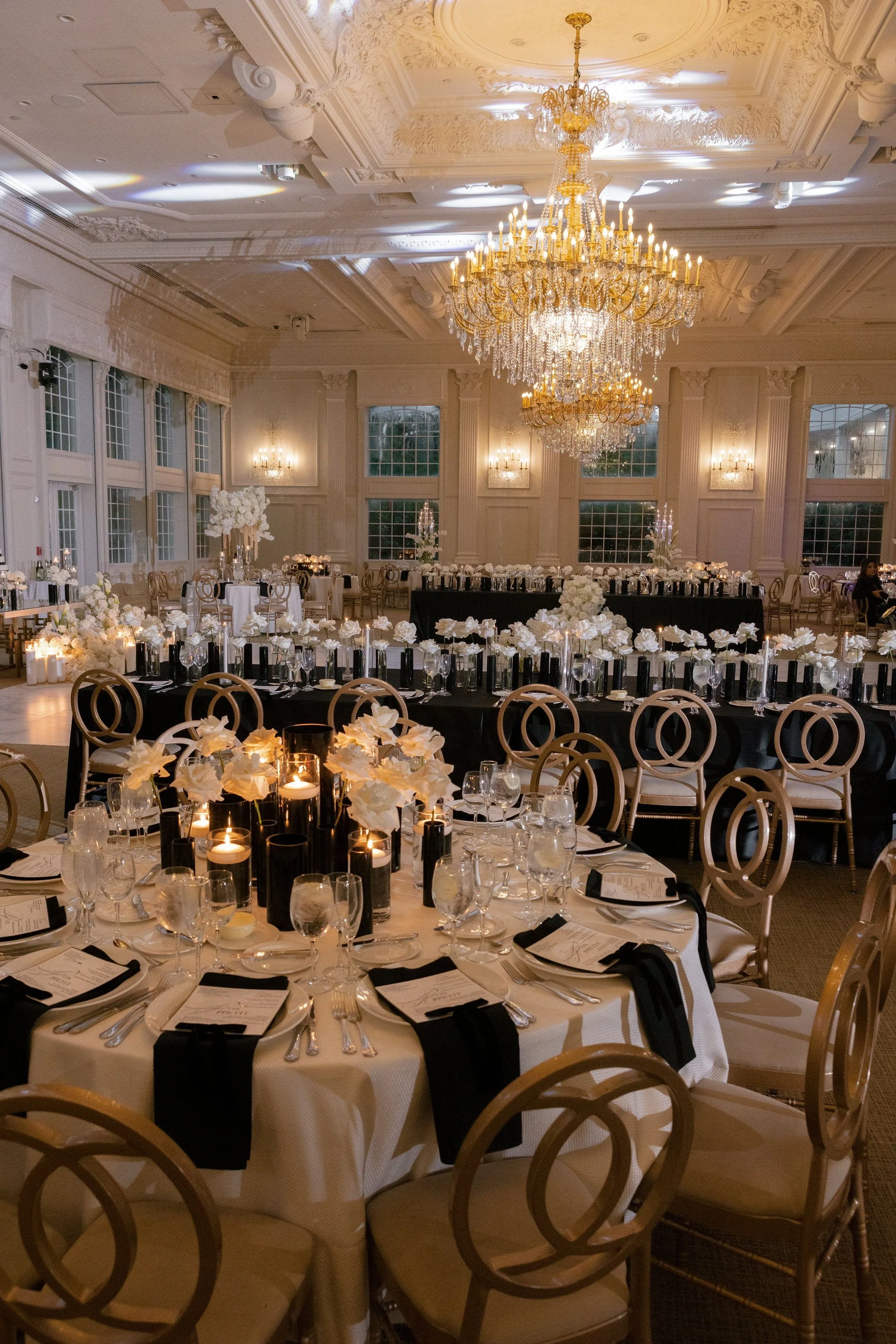 Luxury ballroom reception with tall floral arrangements, candlelight and elegant table settings