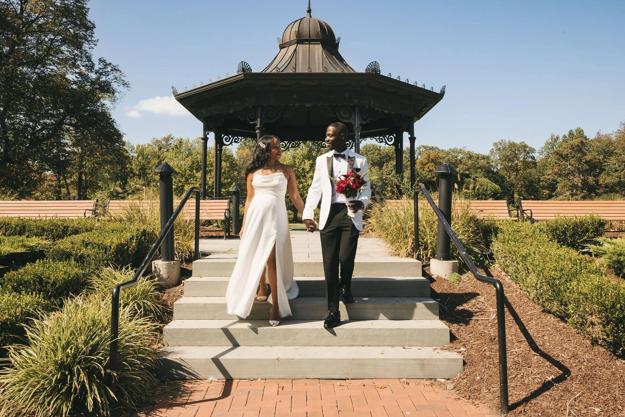 Newlywed couple walking hand in hand after their intimate elopement ceremony at the gazebo at Eagle Rock Reservation in West Orange, New Jersey.