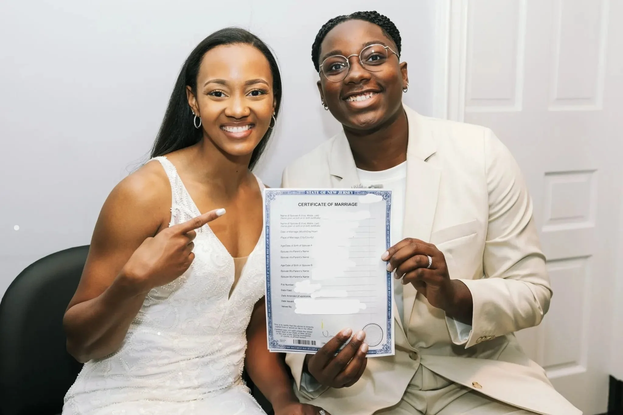Jaide and Amiaya smile while holding their same-day certified marriage certificate after their New Jersey wedding.