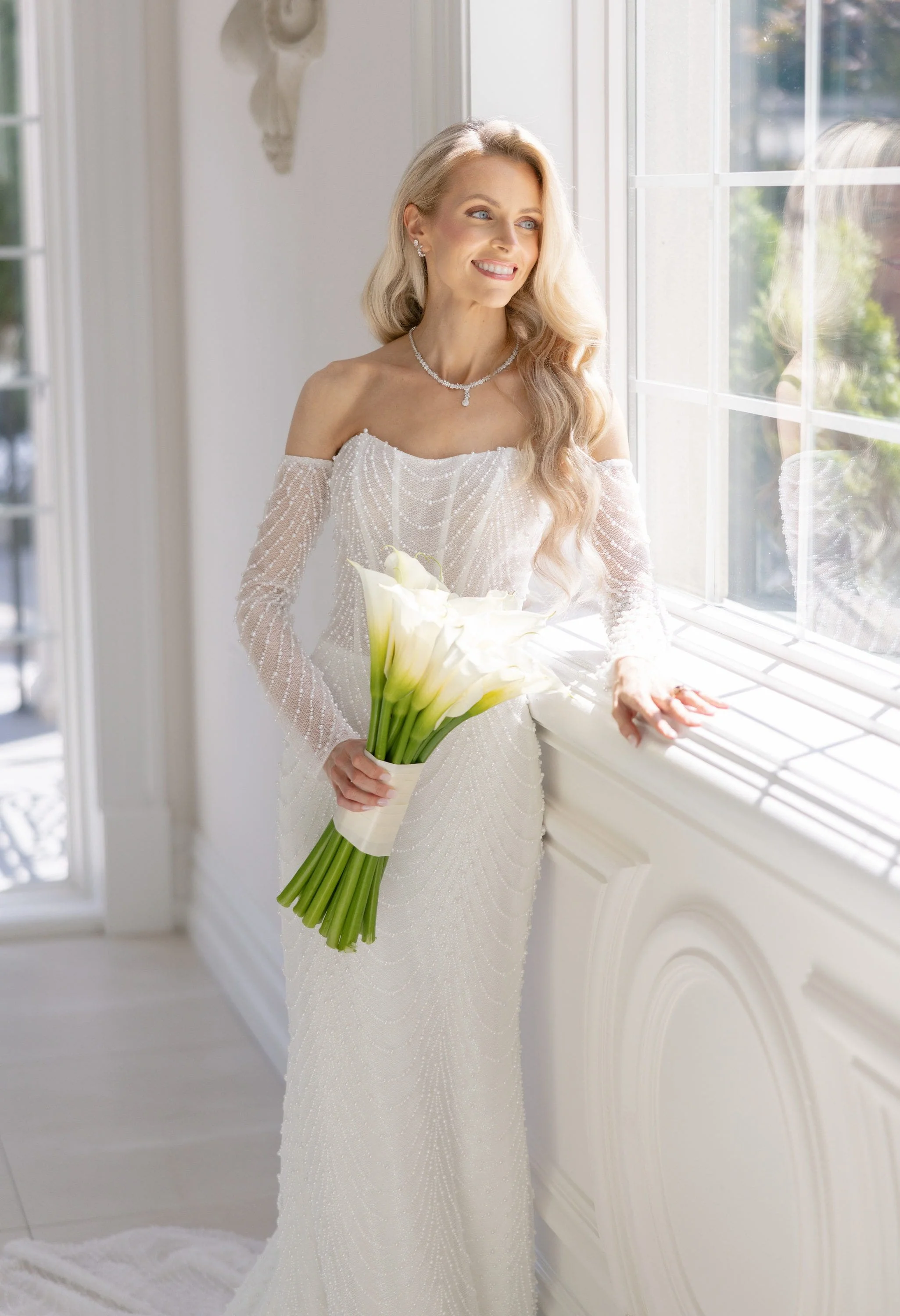 Caroline holding her white calla lily bouquet in a bridal portrait before the wedding ceremony