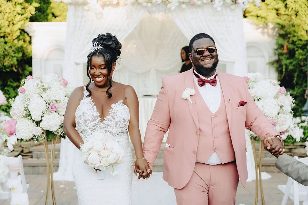 Kristie and Gillon smiling as they walk back down the aisle together after their Sand Castle wedding ceremony in Franklin Square, NY