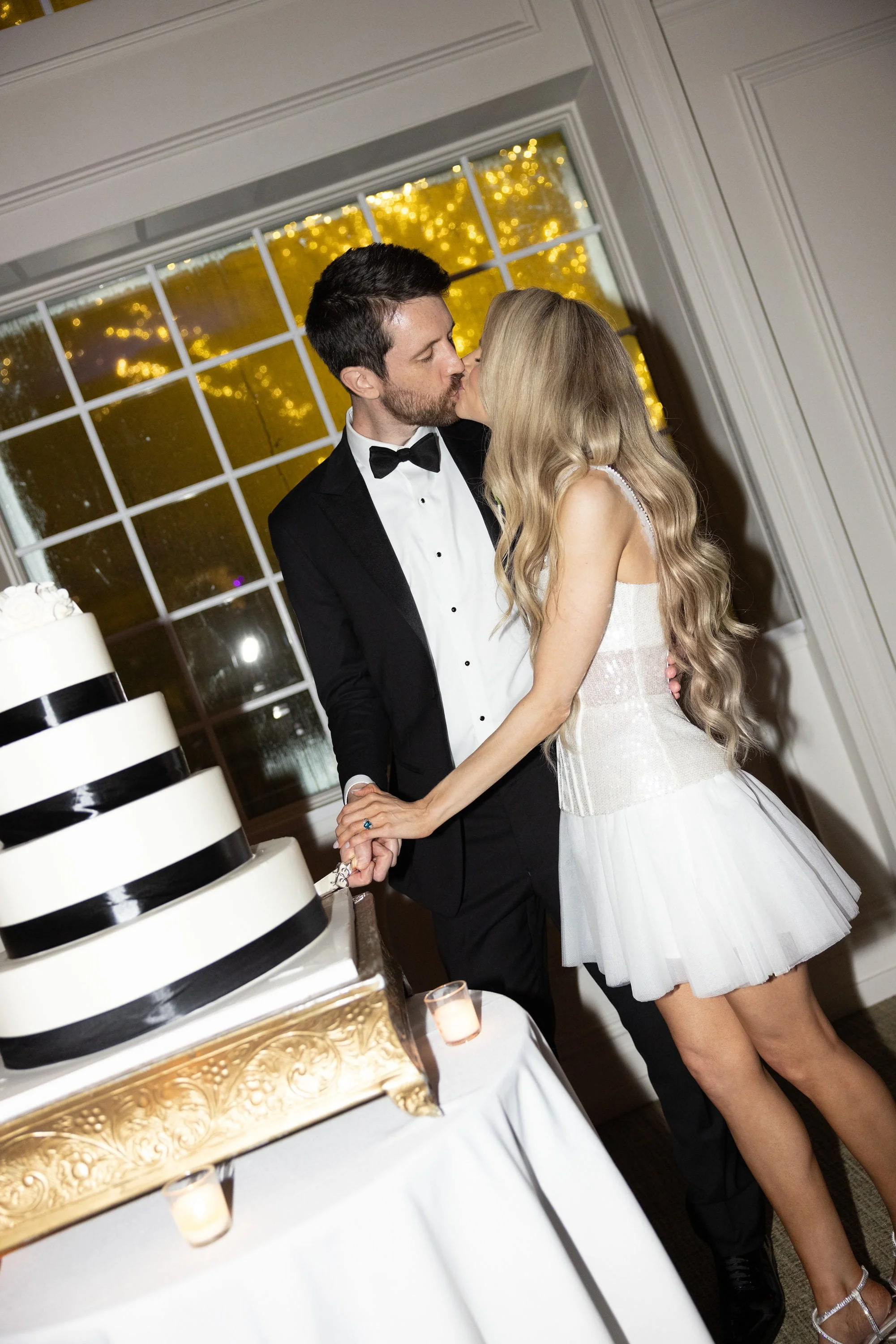 Caroline and Brett kissing as they cut their wedding cake during the reception