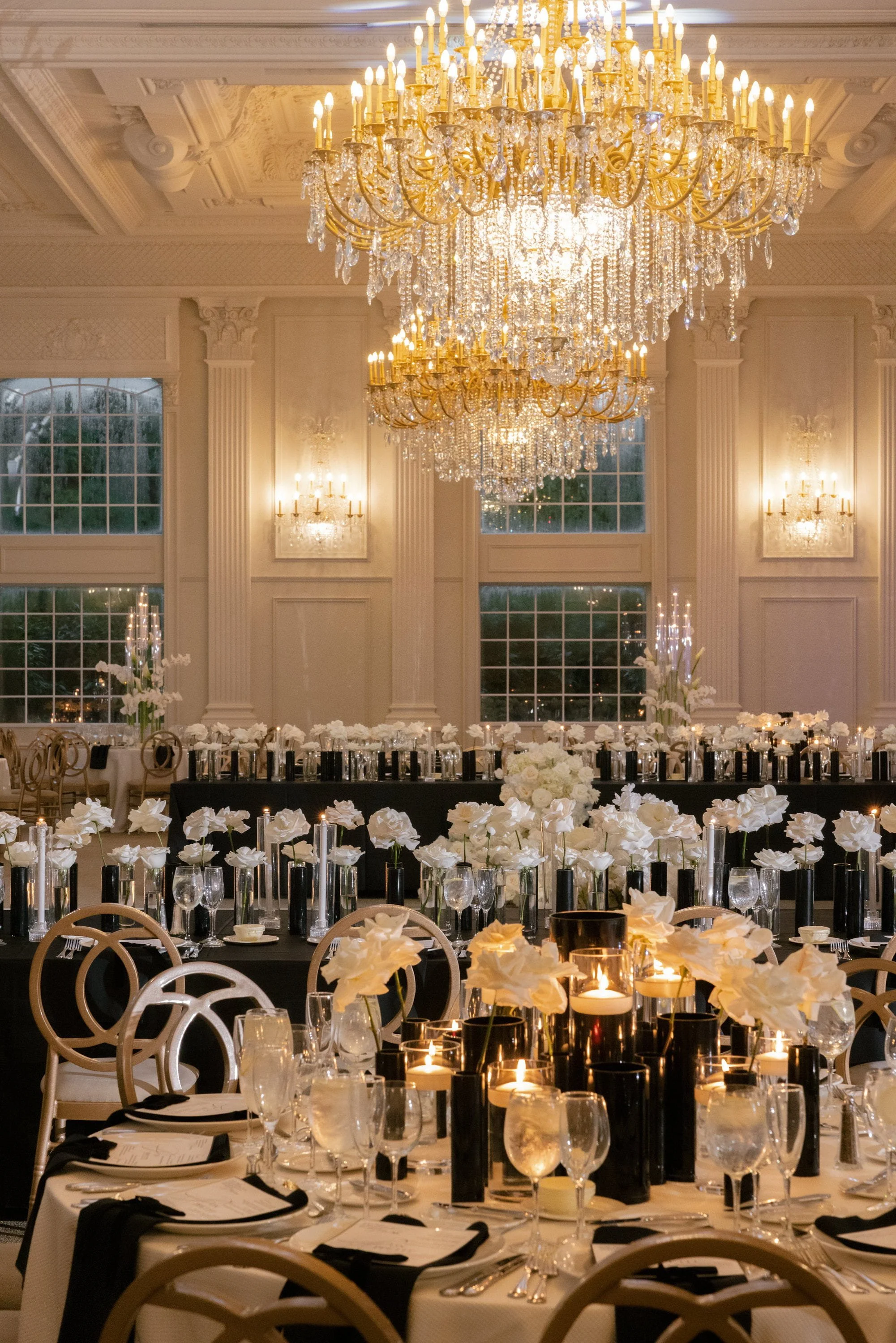 Elegant ballroom reception décor with crystal chandeliers, candlelight and white floral arrangements
