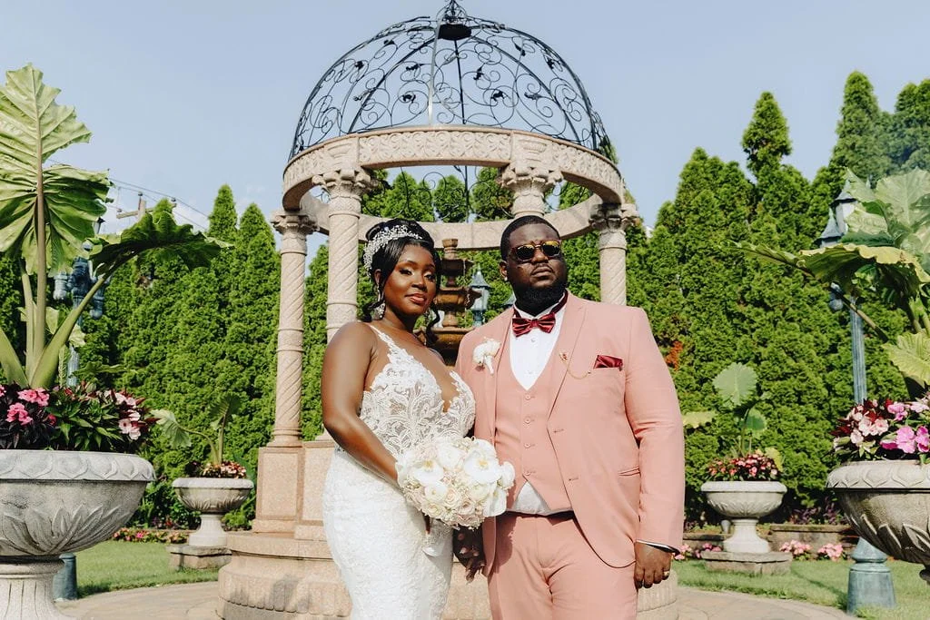 Kristie and Gillon posing in the gardens at Sand Castle in Franklin Square, NY on their wedding day