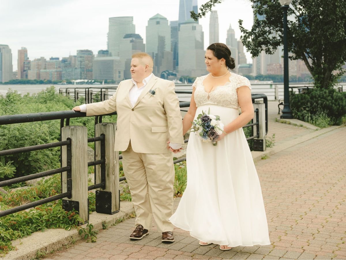 Couple holding hands during their Liberty State Park elopement with waterfront views and the New York City skyline behind them