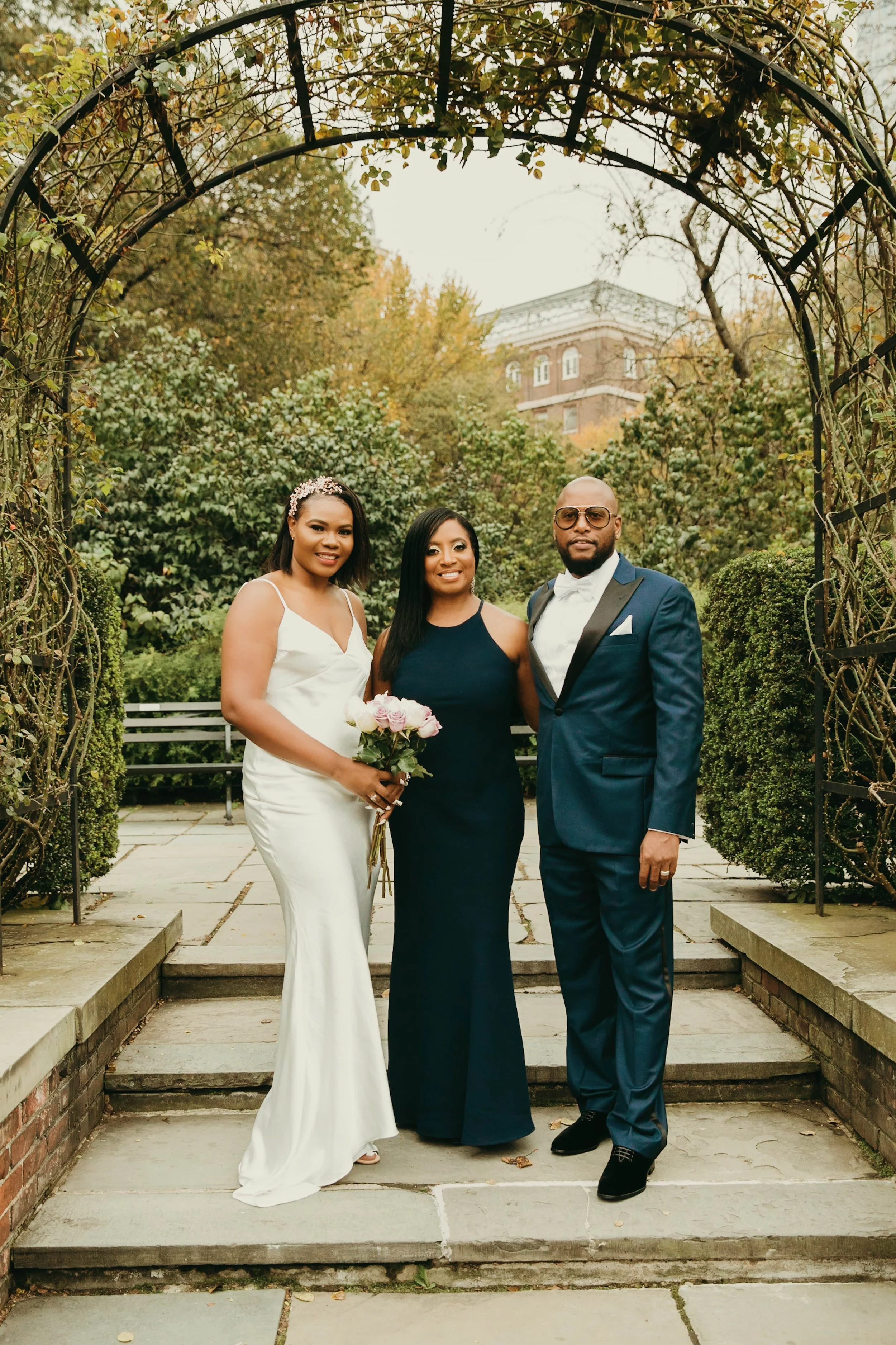 Newly married couple with their wedding officiant after their elopement ceremony at Conservatory Garden in Central Park, New York City.