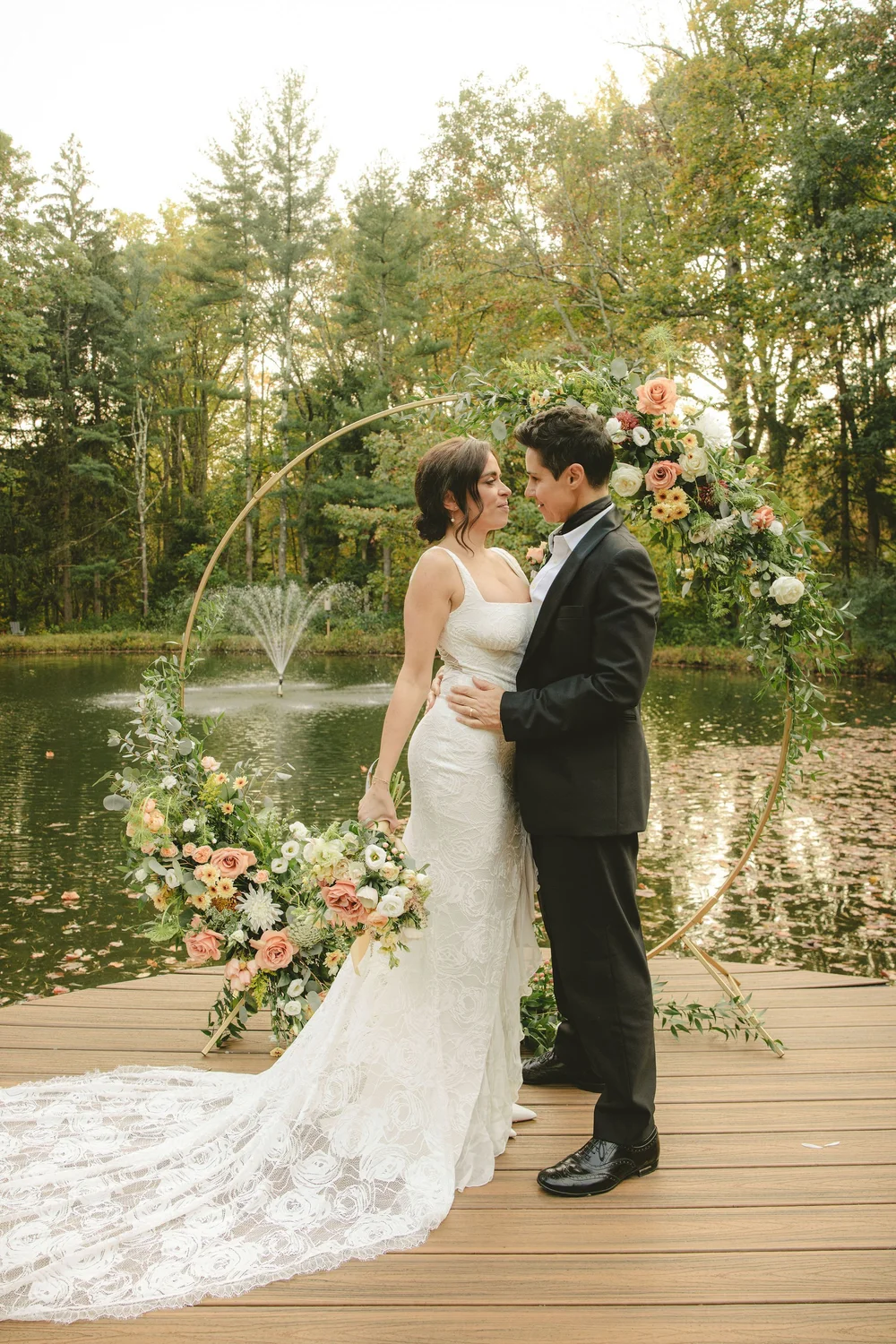 Susie and Annie under a floral arch on a lakeside dock in Bernardsville, NJ