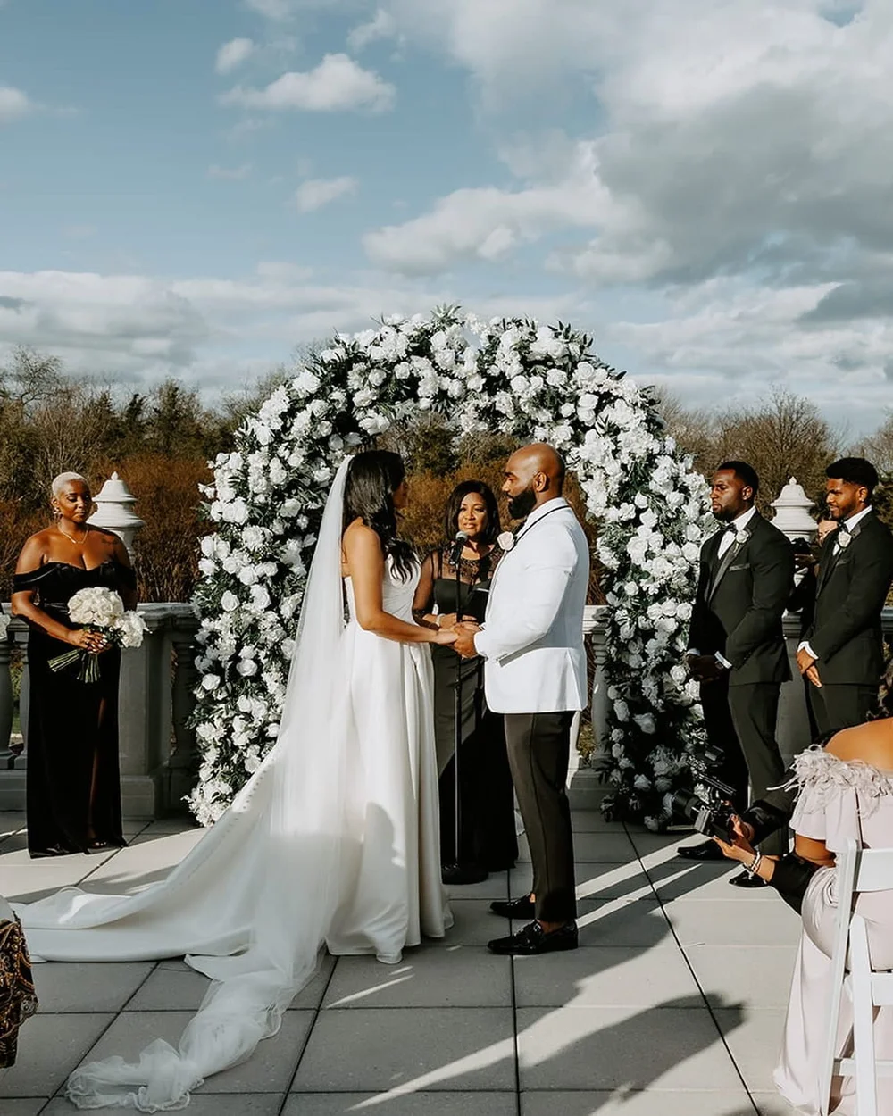 Yadilsa and Berkat under a white rose arch at The Palace at Somerset Park in Somerset, NJ