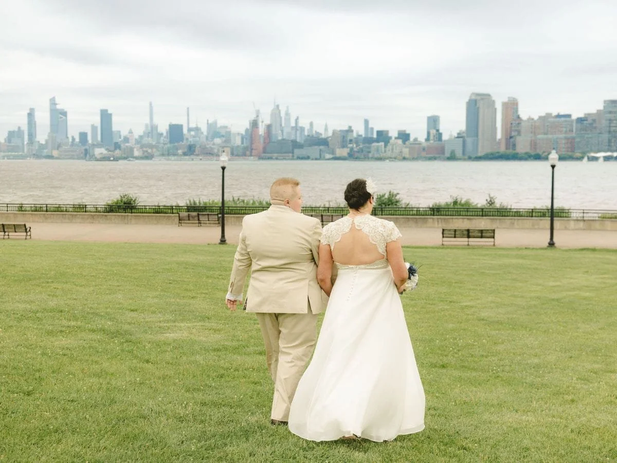 Couple walking across the lawn after their Liberty State Park elopement with the New York City skyline in the distance