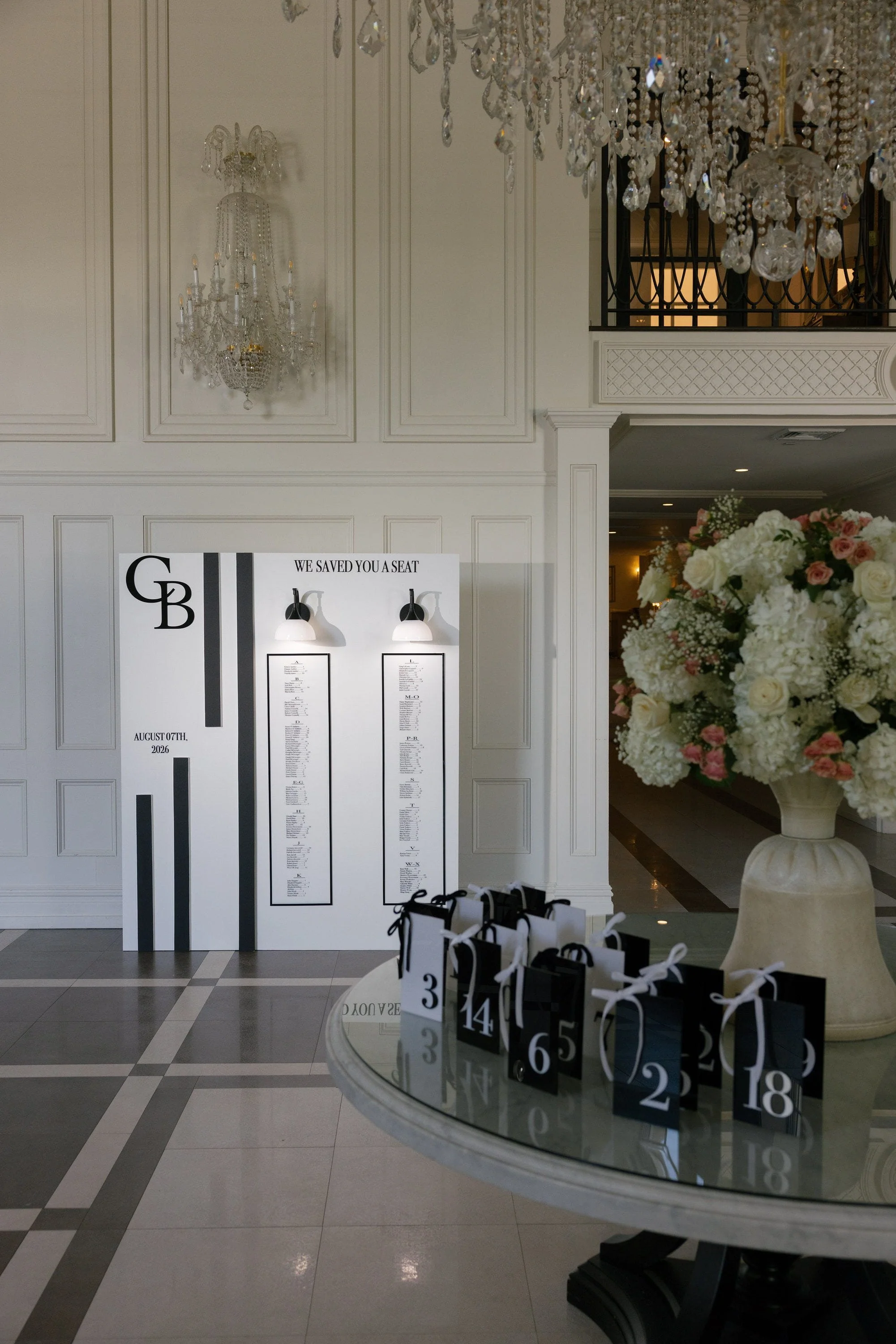 Wedding seating chart, floral arrangement and guest favor bags displayed at the Florentine Gardens reception