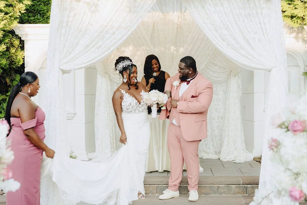 Wedding officiant Aretha Gaskin shares a joyful moment with couple Kristie and Gillon during their outdoor wedding ceremony at The Sand Castle in New York.