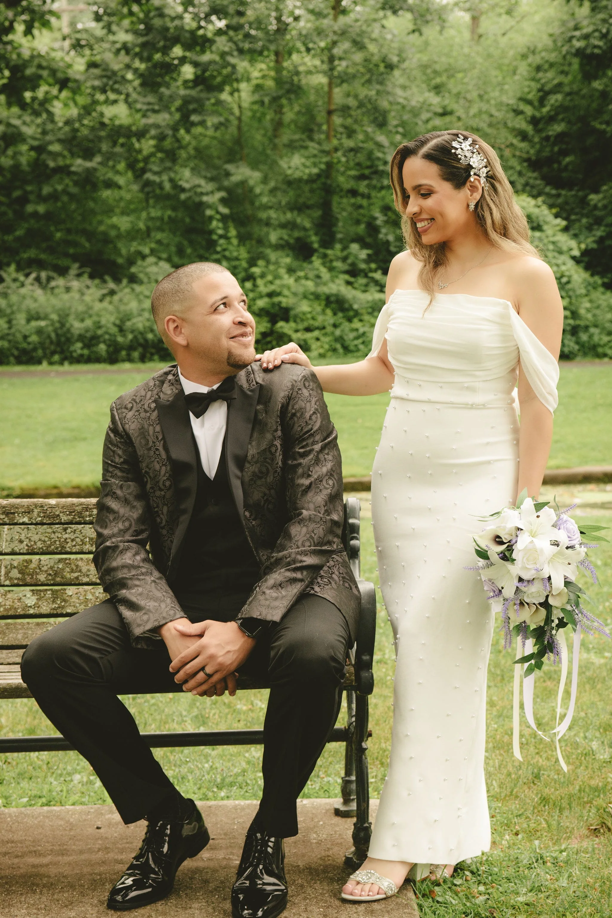Newlywed couple sharing a quiet moment by a park bench after their elopement at Mindowaskin Park in Westfield, New Jersey