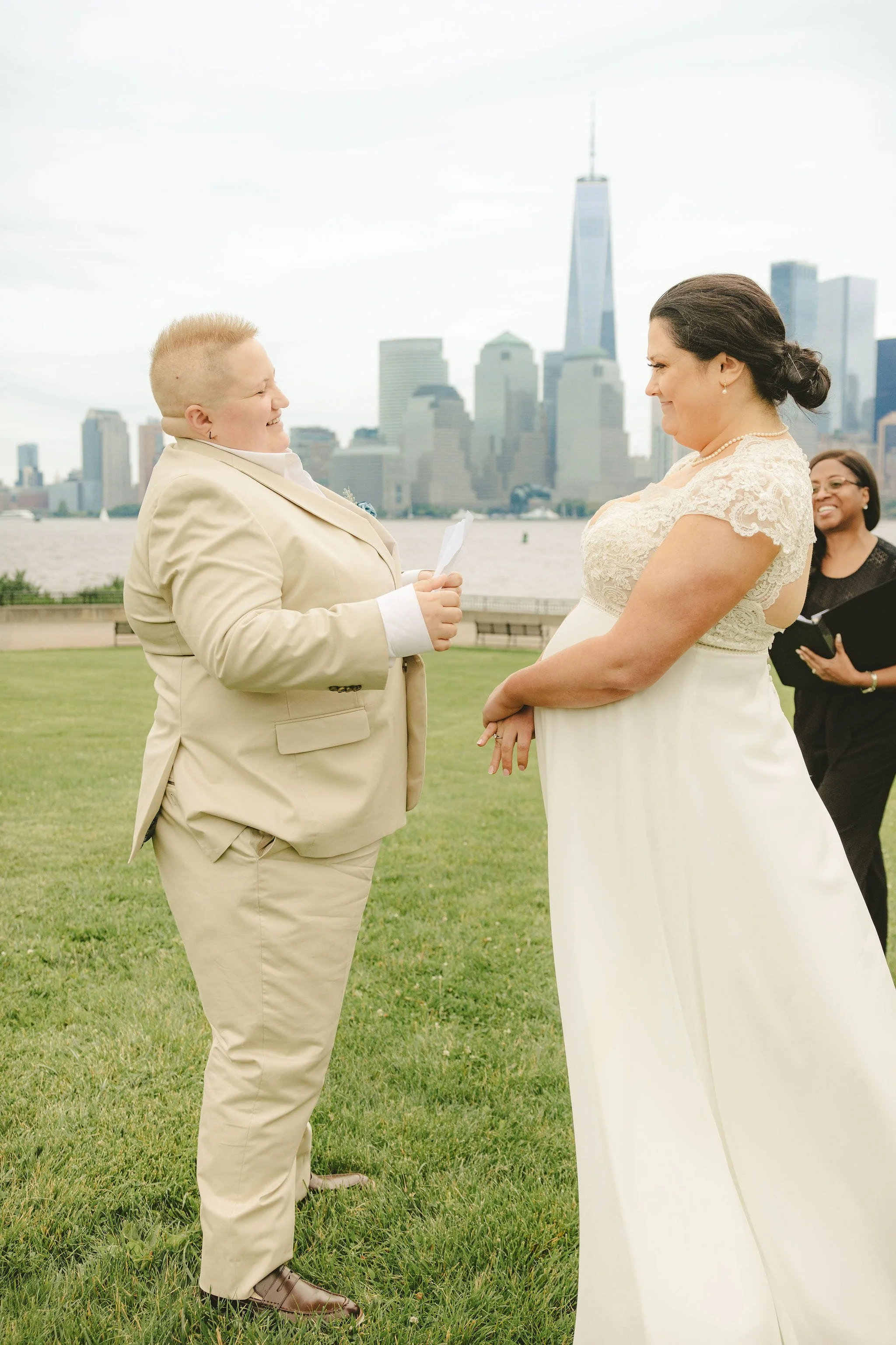 Couple exchanging vows during their Liberty State Park elopement ceremony with officiant and New York City skyline behind them