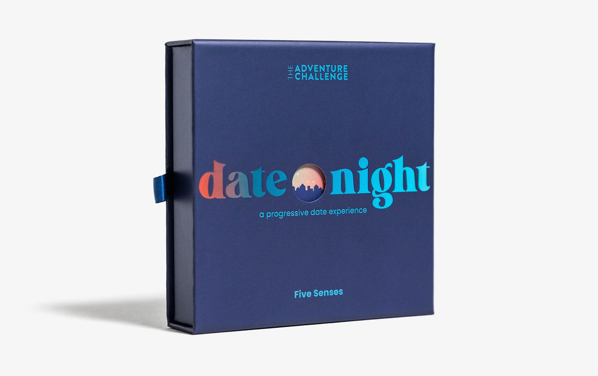 A blue product box with the words "Date Night a progressive date experience Five Senses" sits upright on a well-lit white background.