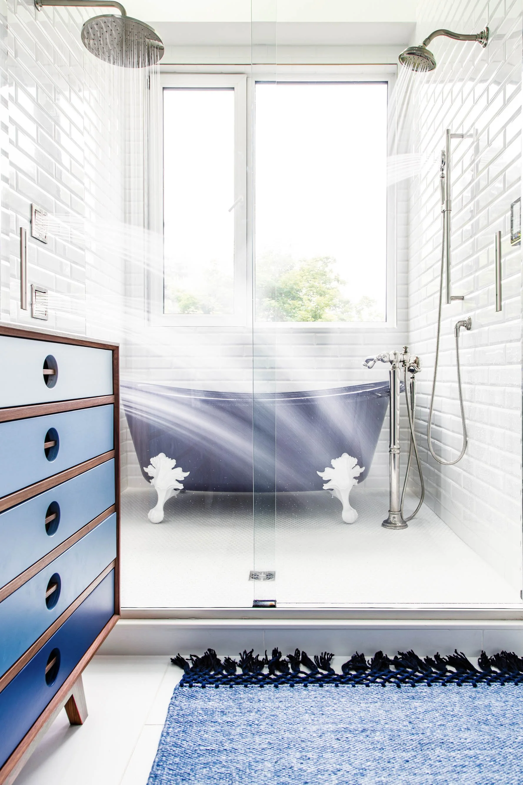 Modern wet room bathroom with clawfoot soaking tub, glass-enclosed shower, and white subway tile walls.