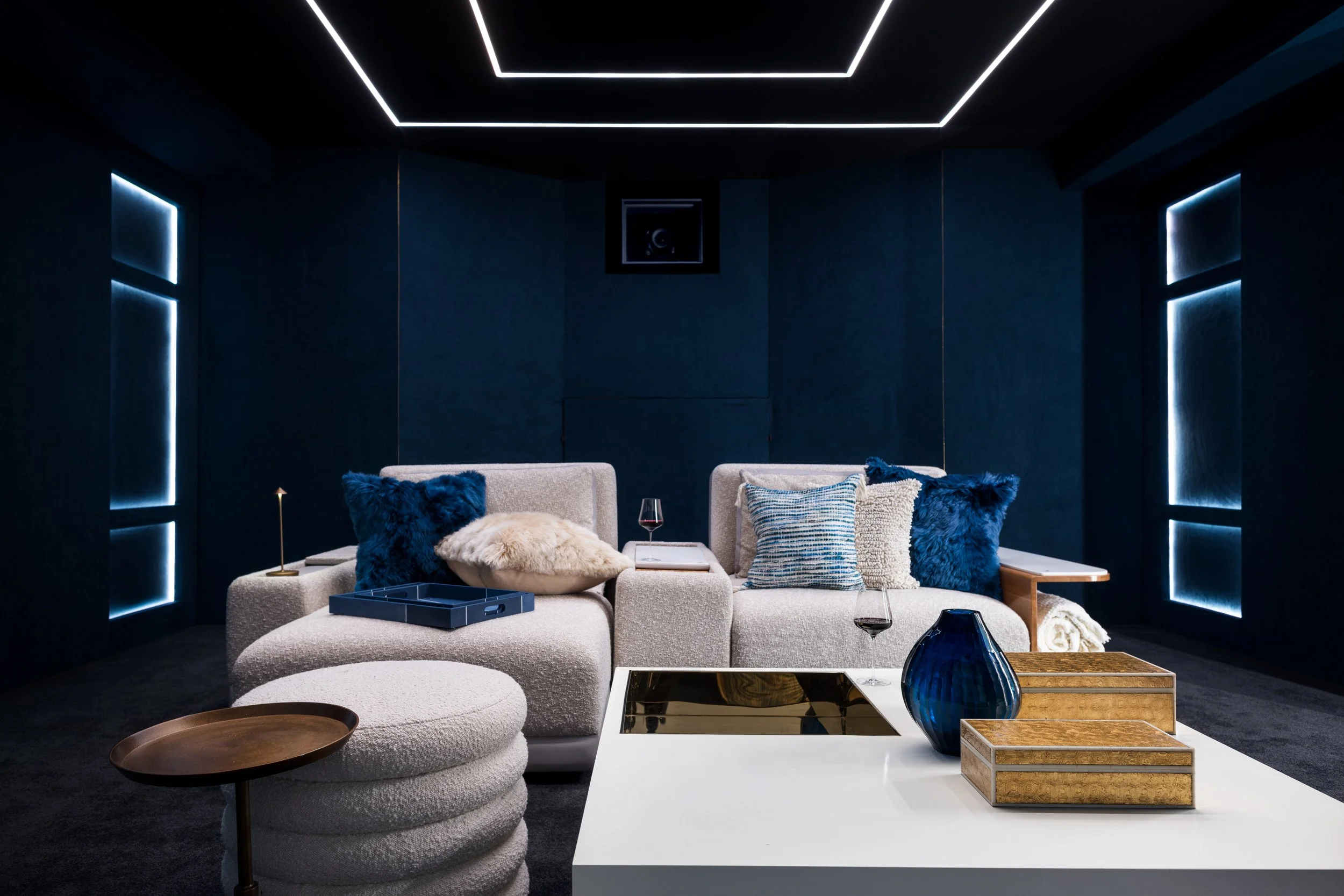 Luxury home theater with custom seating, integrated LED lighting, and dark tonal interiors.