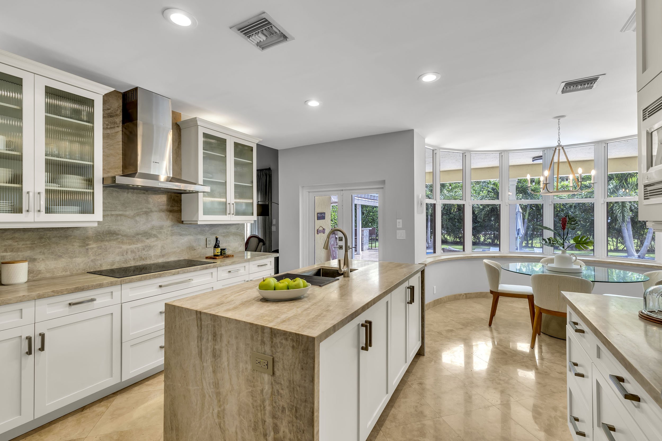 Kitchen featuring a leathered finish marble countertop with waterfall edge, continued seamlessly into the backsplash. Cabinetry painted in Alabaster by Sherwin Williams.