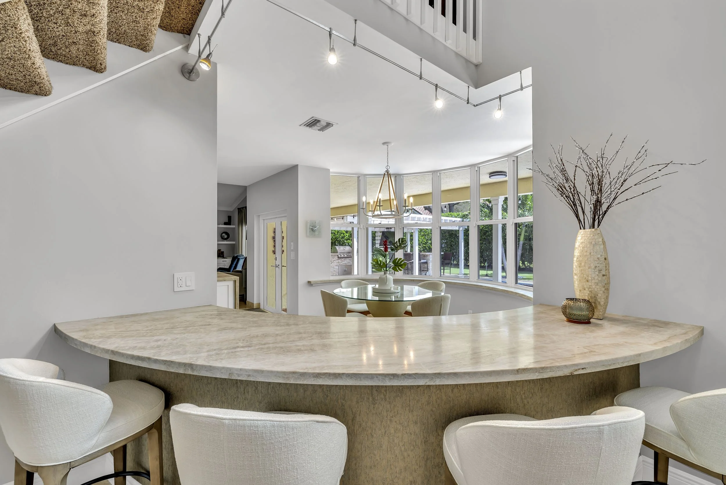 Custom dry bar featuring honed marble stone countertop and a wallpapered front face. Walls painted in City Loft by Sherwin Williams. Cream upholstered wood barstools from City Furniture complete the look.
