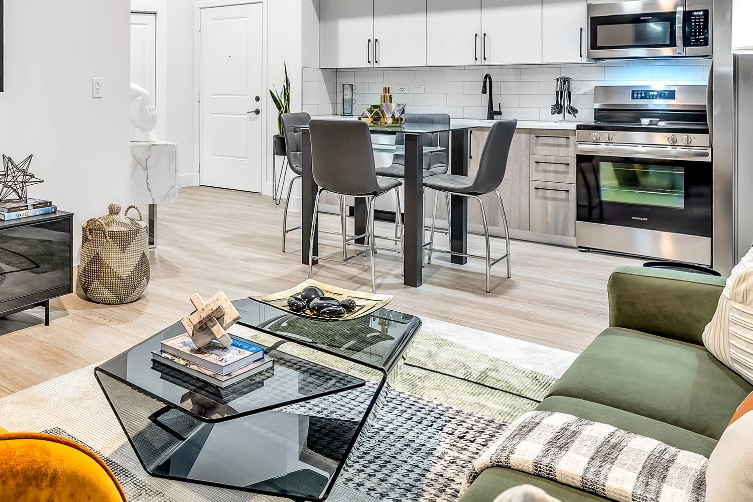 Wide shot of contemporary home with open floor plan; primary colors that pop are green and orange, with many neutral accents.