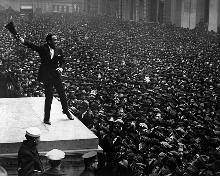 Douglas Fairbanks, movie star, speaking in front of the Sub-Treasury building, New York City, to aid the third Liberty Loan. • Wiki Commons (Image photoshopped with Snelgraphix branding rainbow.)