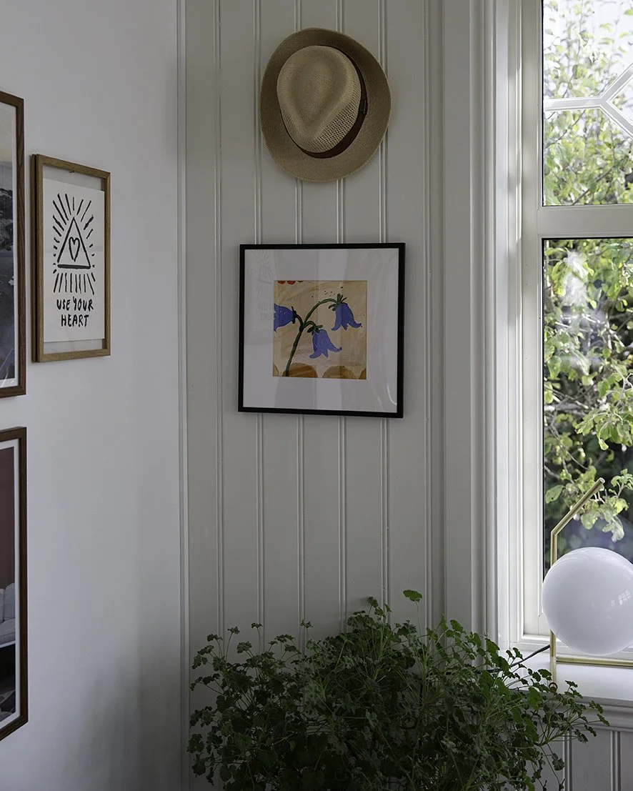 An original acrylic painting in a living room by Sonja Dahlgren of three expressive bluebells on a yellow ochre background