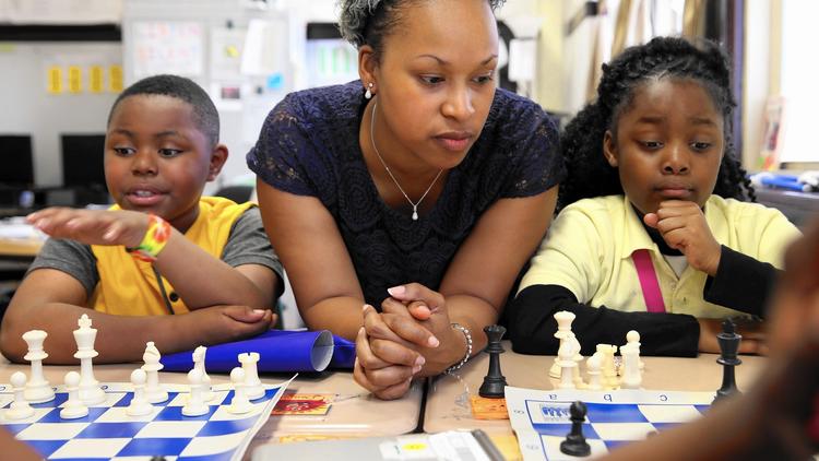 Candice Usher, center, a teacher at Fuller School of Excellence in Chicago, shows students Charleston Rice, left, and Nic'Kita Williams, right, how to play chess. (Terrence Antonio James / Chicago Tribune) Copyright © 2017, Chicago Tribune