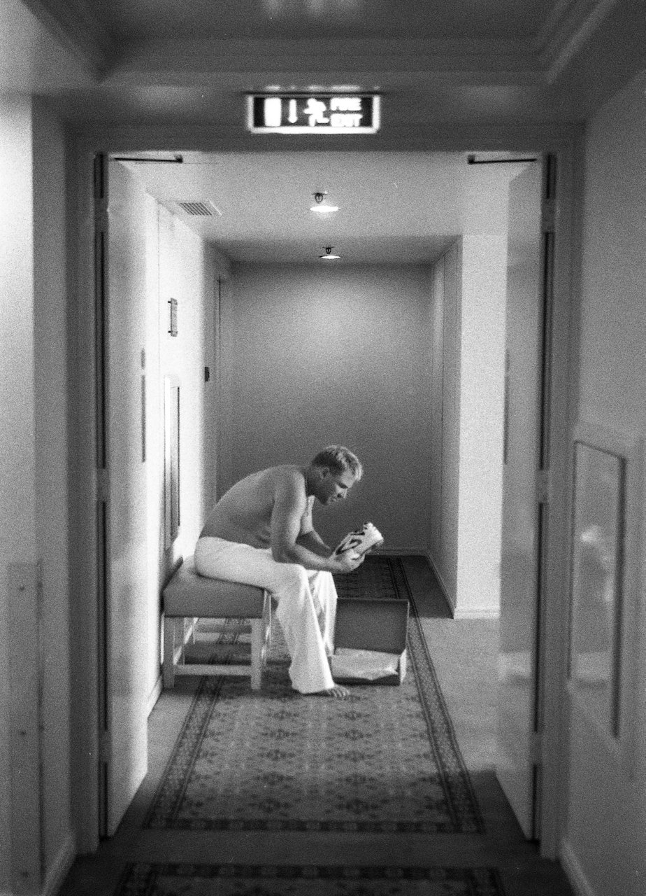 Shane Warne checking new boots while his baby child sleeps in his hotel room, Birmingham, August 2001