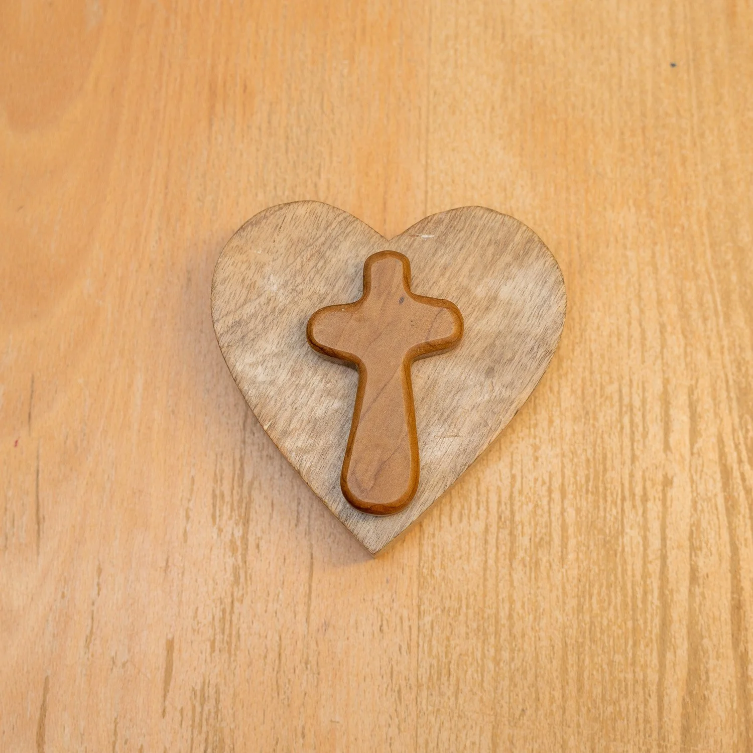 A wooden heart carved from wood to signify love, combined with a cross to represent growing and developing with faith