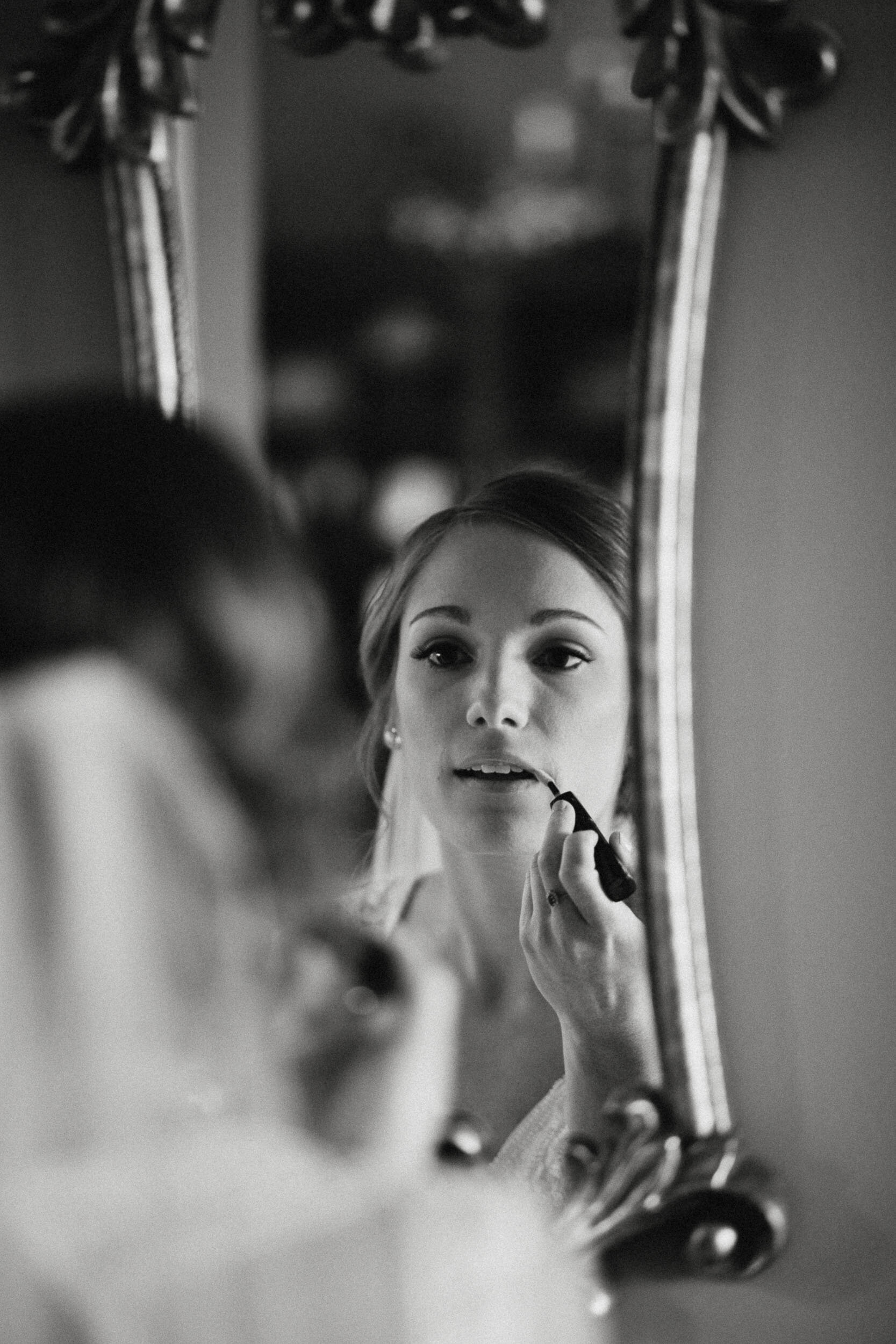 Bride applying lip gloss in mirror in Dayton Ohio.