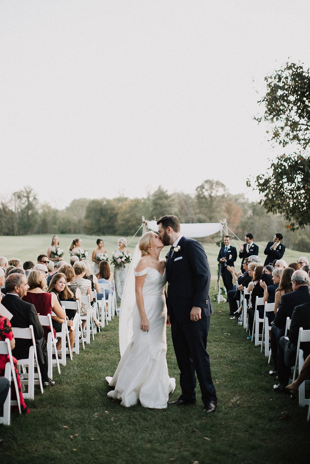 Bride and groom kissing in aisle outdoor ceremony