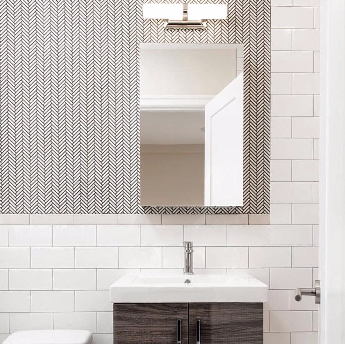  Bold herringbone tile and sleek storage solutions give this New York City bathroom a clean and modern aesthetic. Design by  @perianth_buymyeye ; photo by  @njohnstonphotography  