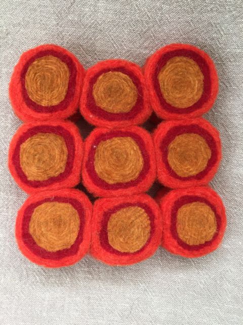 Trivet made by stitching together slices of wool layers tightly rolled and wet felted.