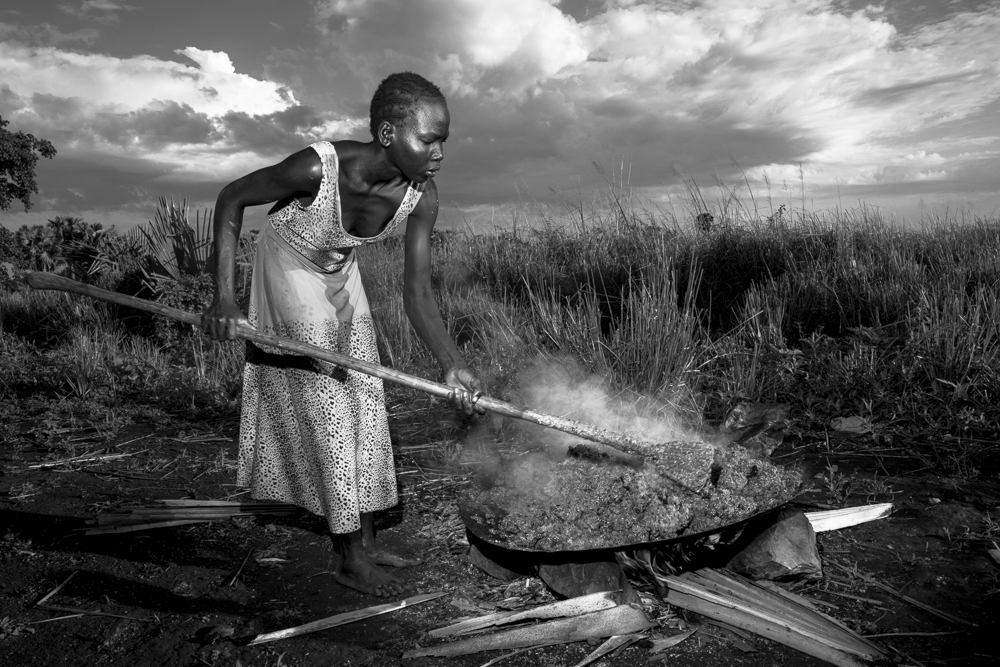 Nuer village woman cooking mash of sorghum and millet